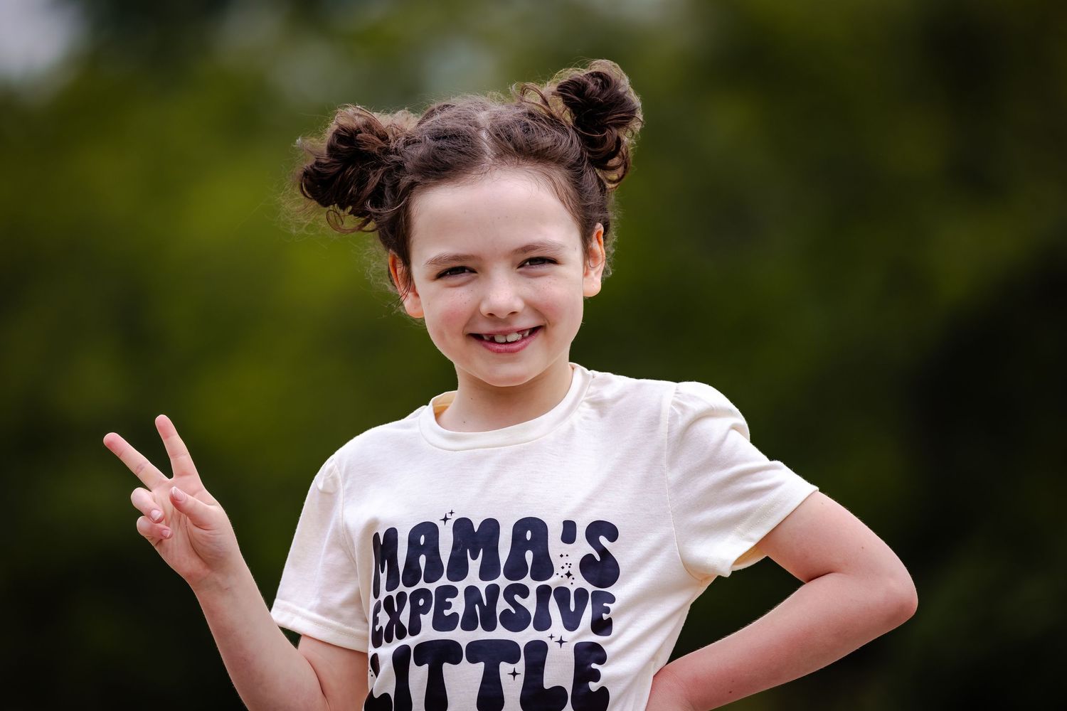Playful outdoor portrait in graphic t-shirt making peace sign gesture.