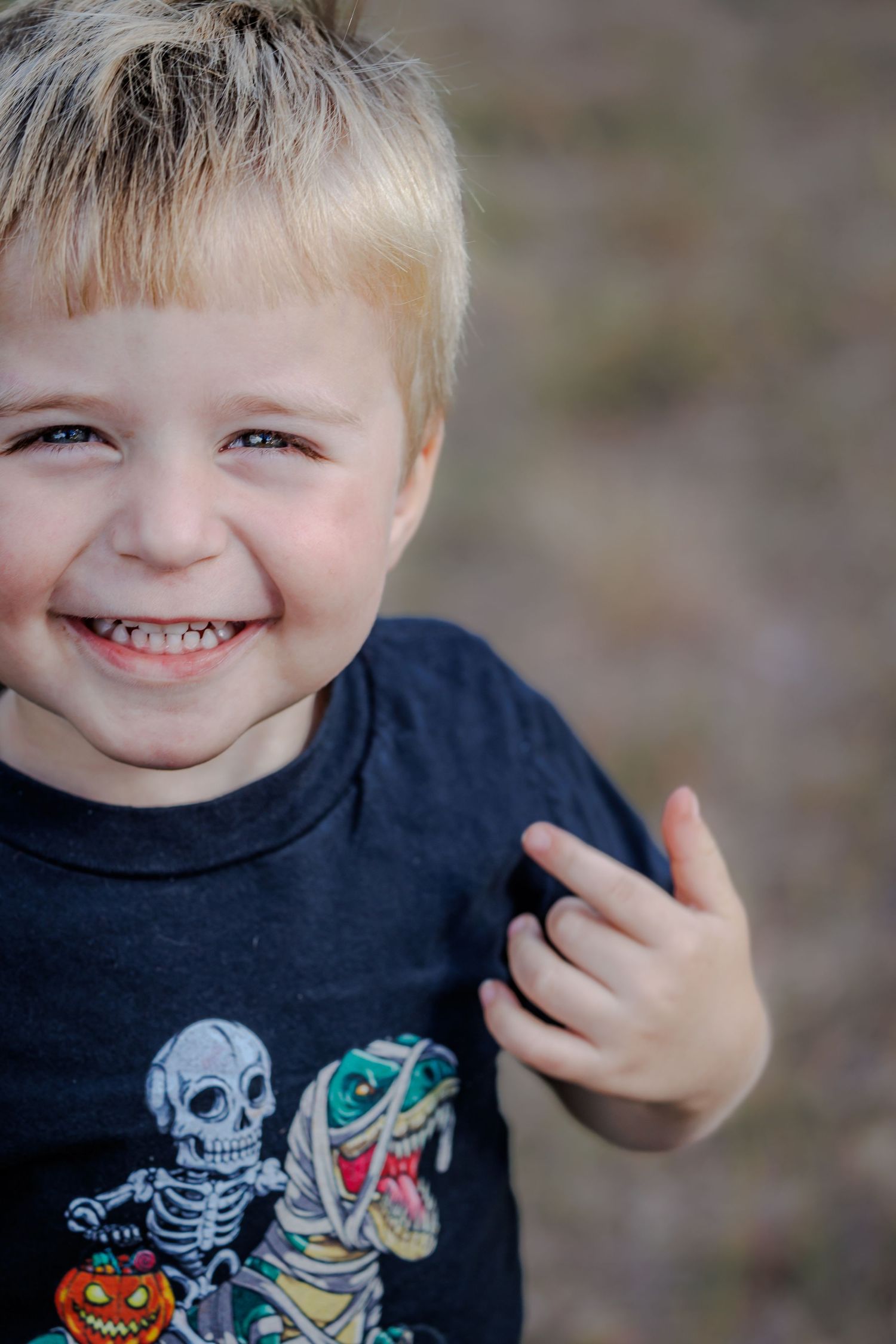 Smiling child wearing a Halloween themed t-shirt with skeleton and mummy graphics.