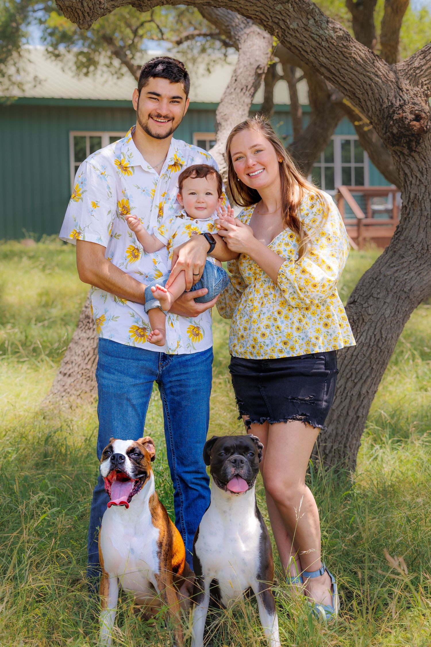 A family portrait with two dogs in a rustic outdoor setting.