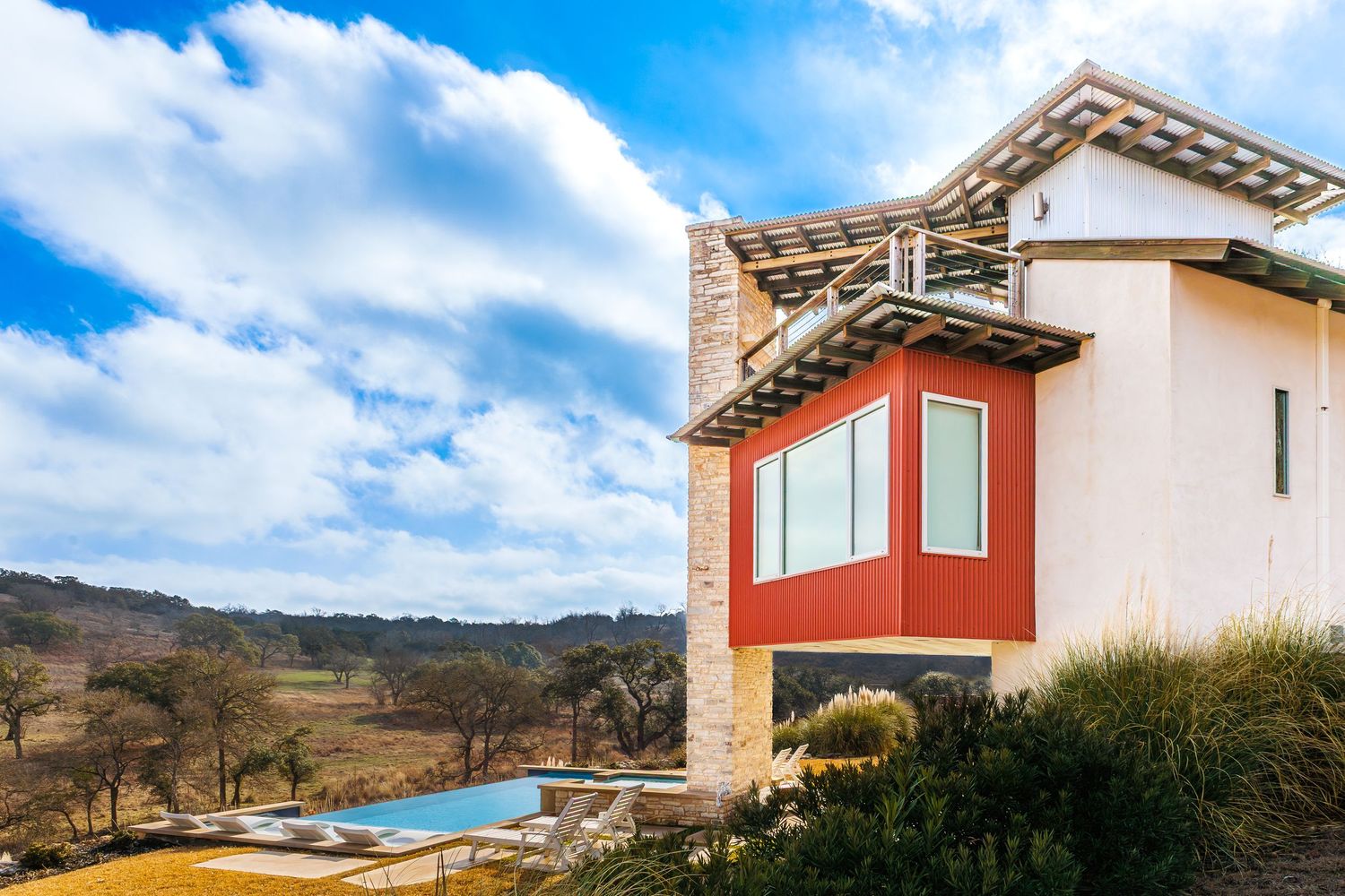 Luxury Texas Hill Country residence with striking architectural design and swimming pool in the background.