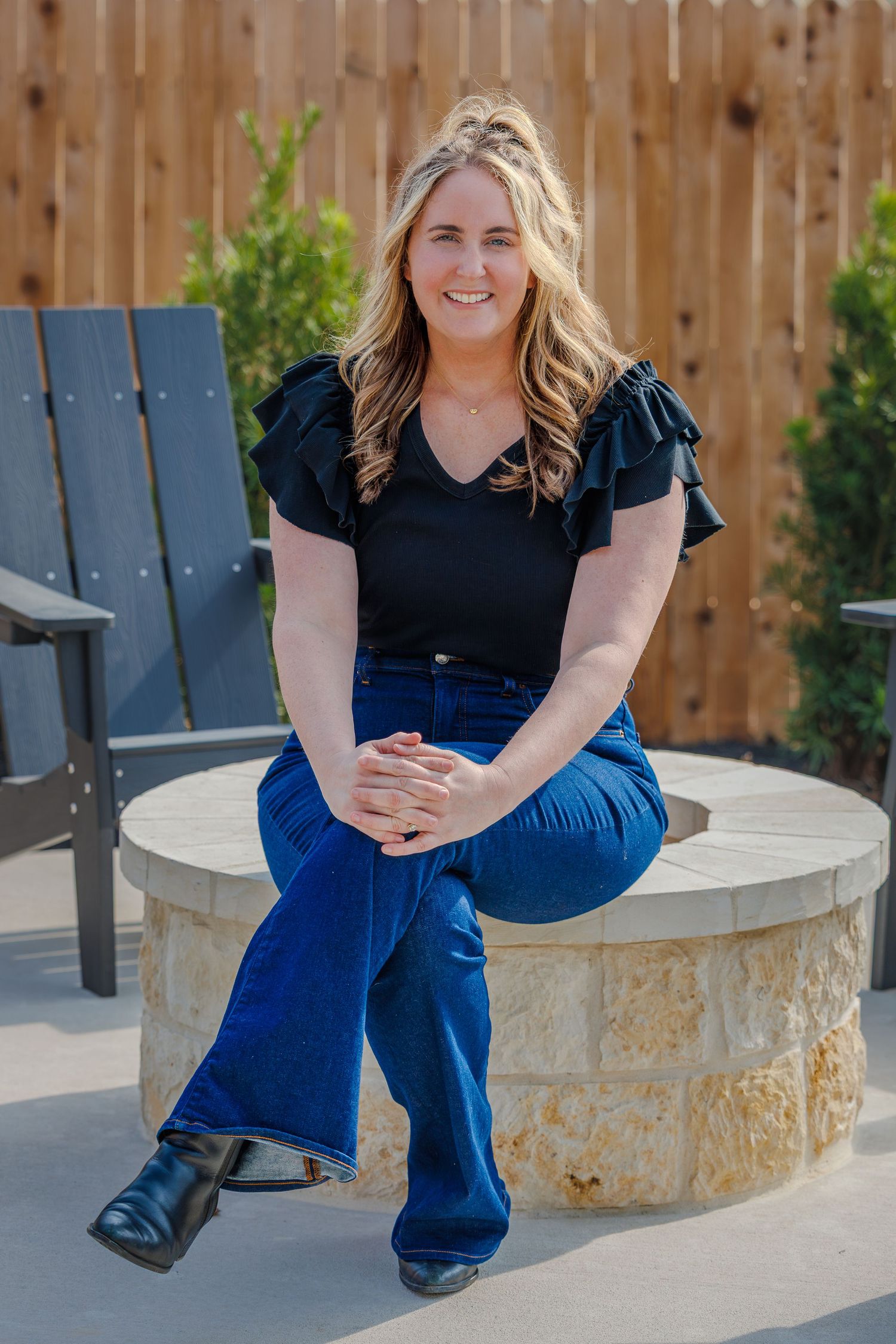Professional outdoor portraits showing casual seated poses on a stone bench against a wooden fence backdrop.
