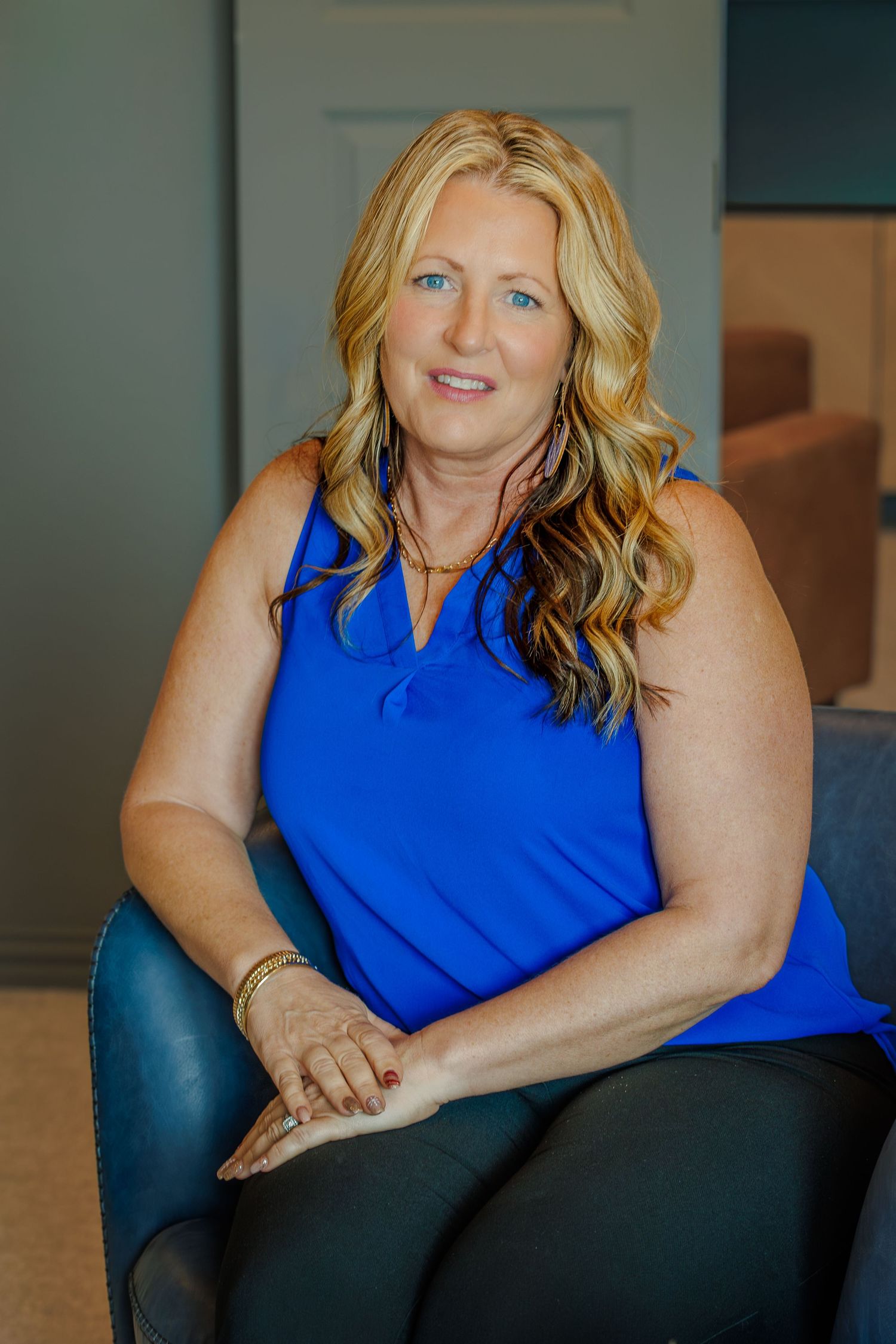 Professional headshot series showing a person in a bright blue sleeveless top seated in a dark chair against a muted background.
