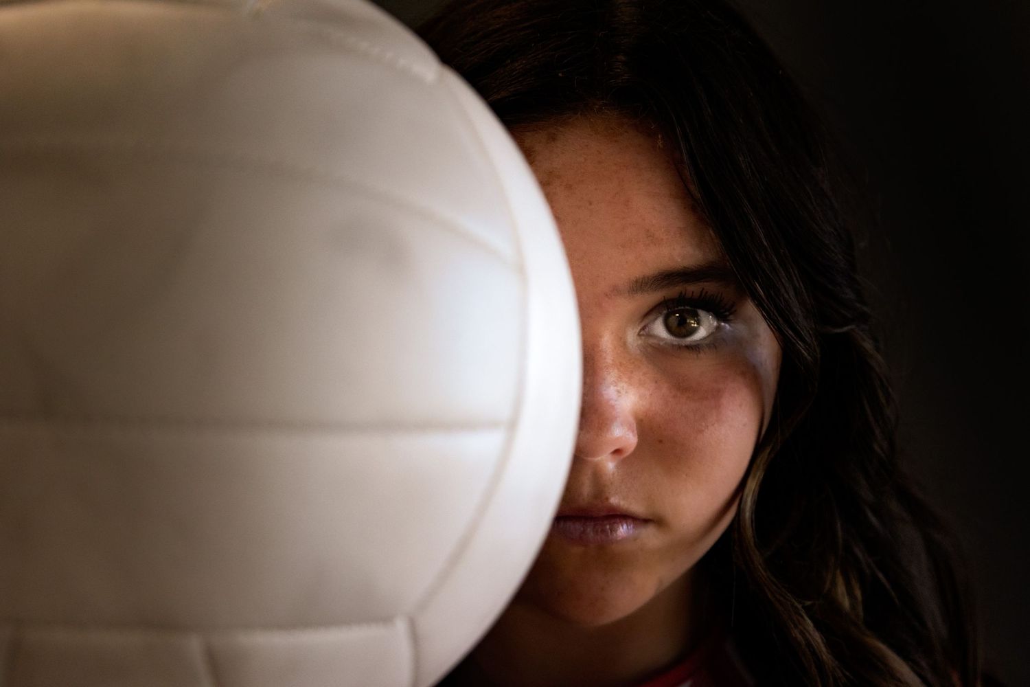Person taking a dramatic selfie portrait series with a white volleyball covering different parts of their face.