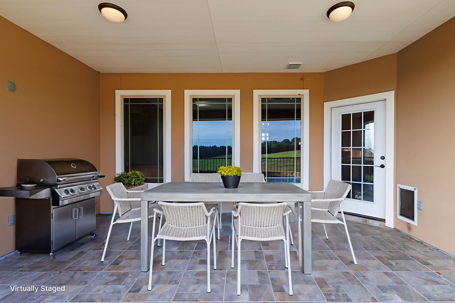 A modern covered patio with white furniture and ceiling fans features a clean, minimalist design and outdoor living space.