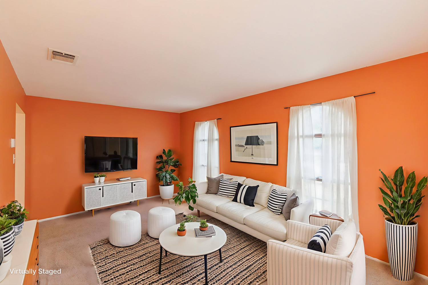 Modern living room with bright orange walls, beige sectional sofa, white media console and decorative plants.