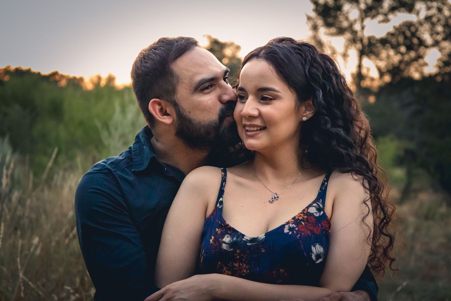 Romantic couple embracing during sunset in a field of tall grass.