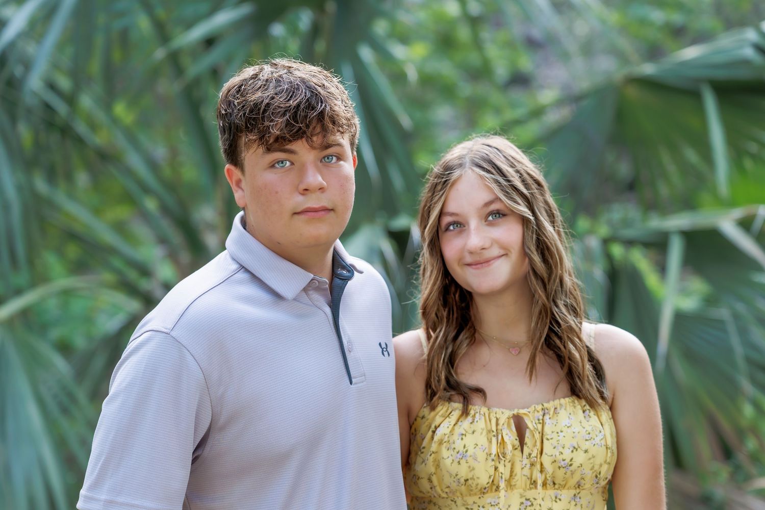 Couple poses together outdoors with tropical foliage background.