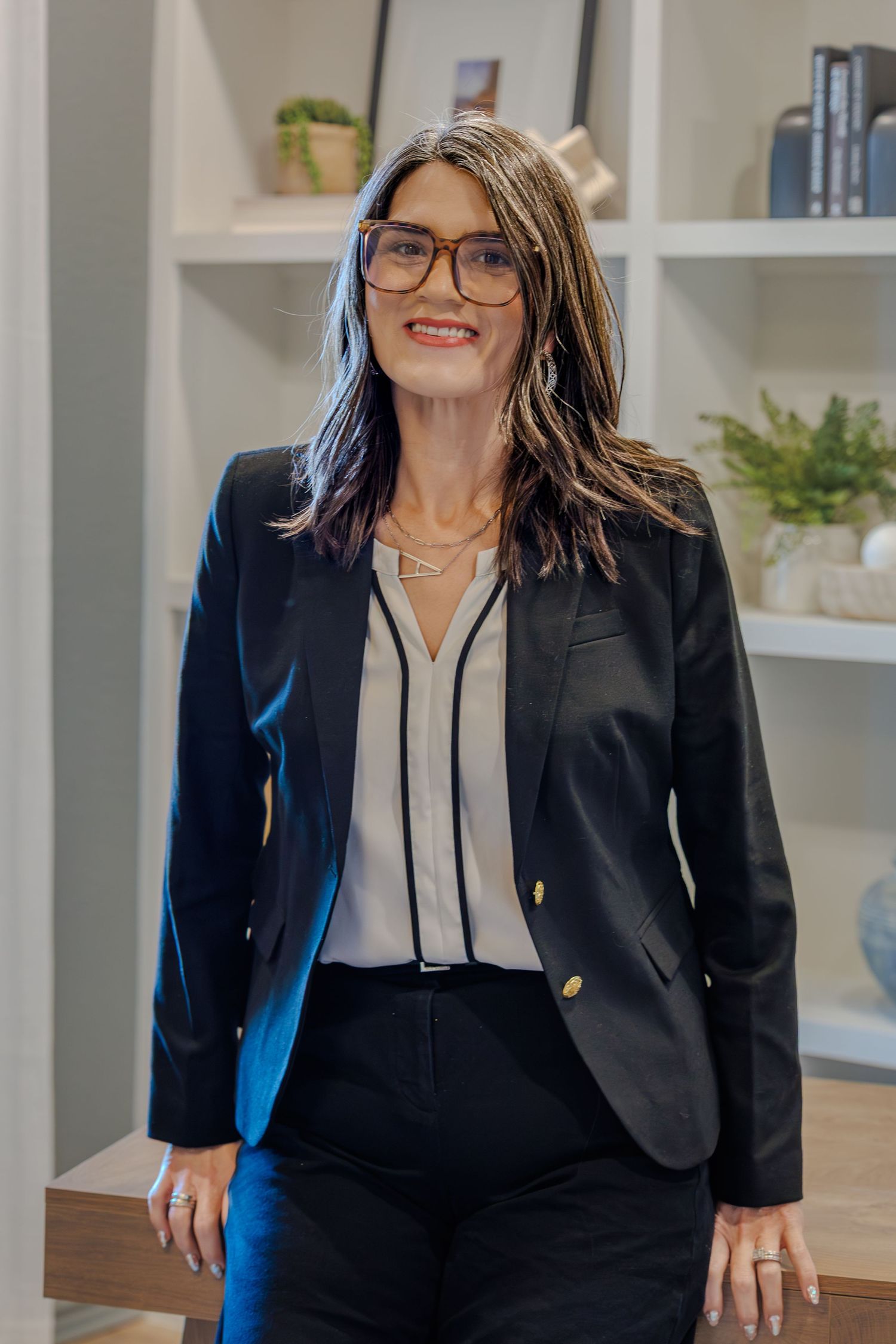 Business professional headshots in a modern office setting with white shelving and decor.