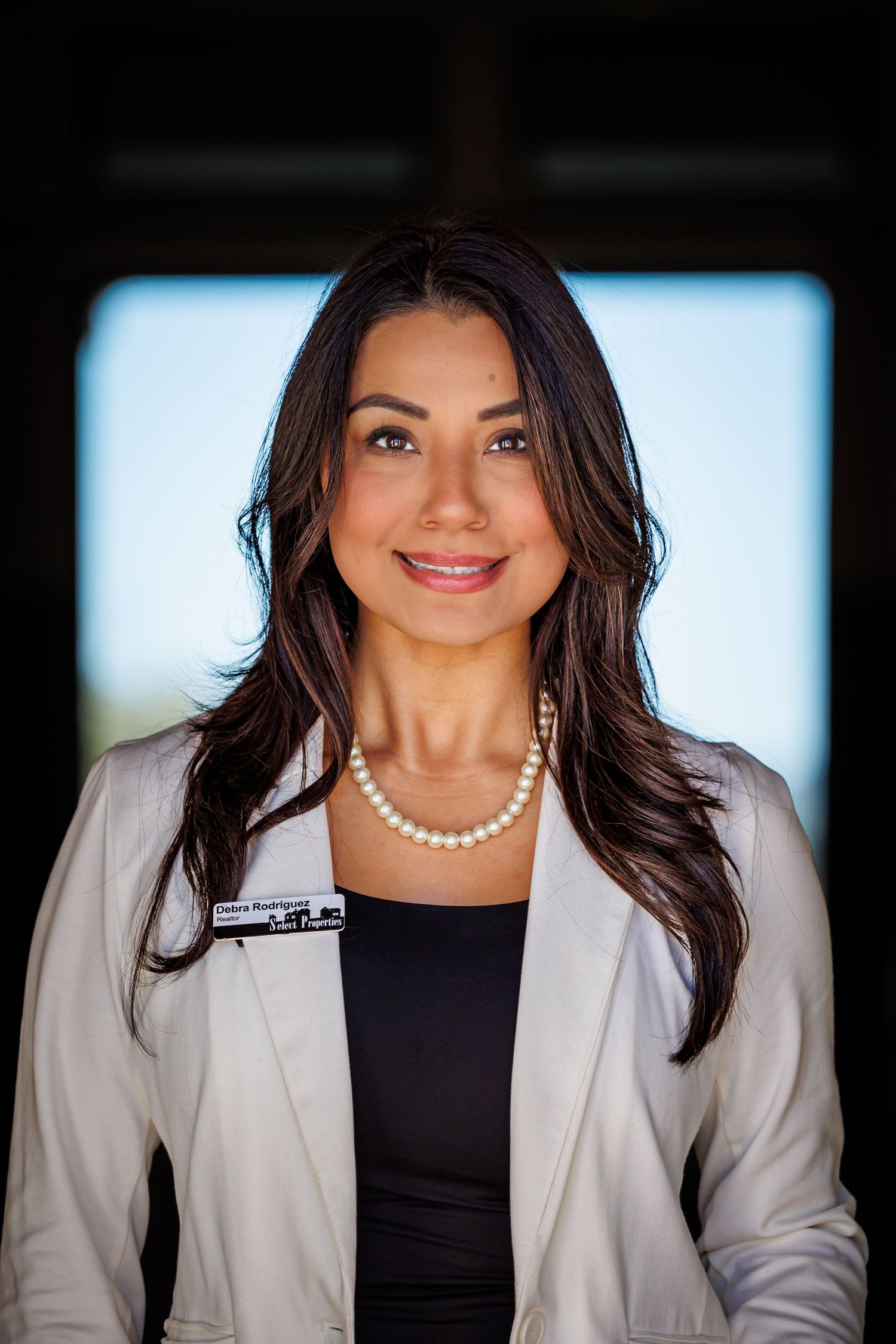 Professional headshot series showing different angles of a person in a light blazer and black top against a blue background.