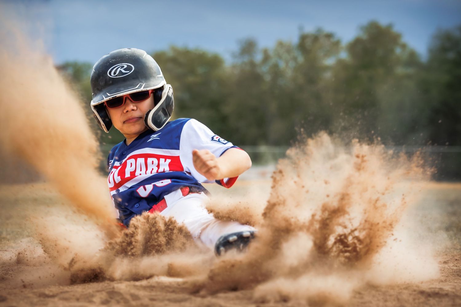 A motocross rider kicks up a dramatic cloud of dirt and dust while sliding through a turn on a dirt track.