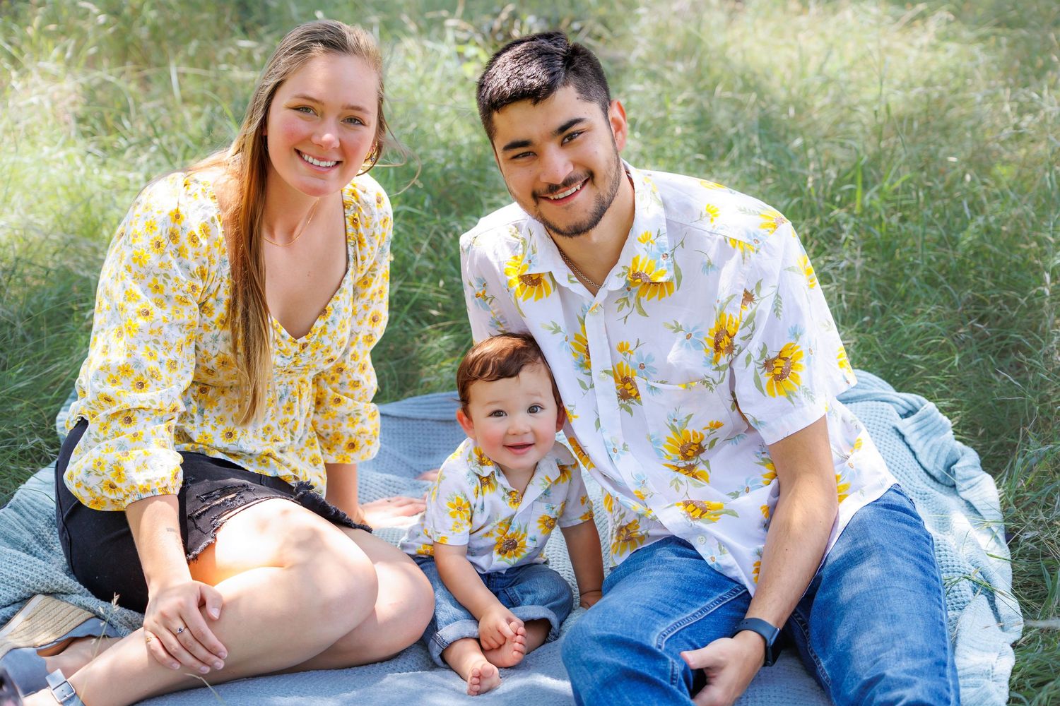 A family sits together wearing matching yellow floral outfits during an outdoor photo session.