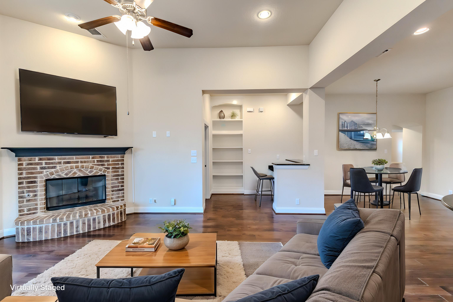 Spacious living room features hardwood floors, brick fireplace, and contemporary seating arrangement.