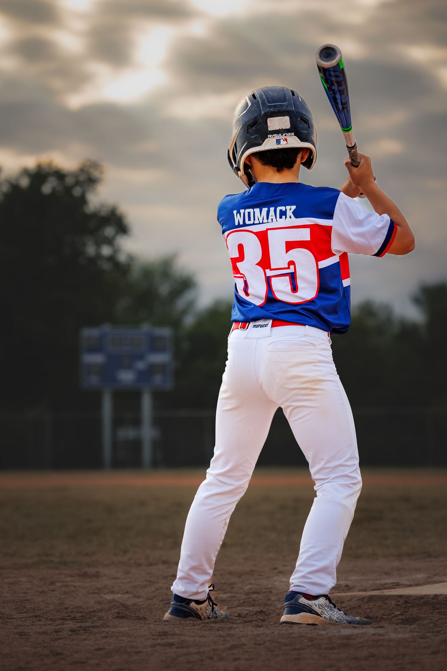 Baseball player in blue and white uniform #35 stands at bat during twilight game on dirt field.