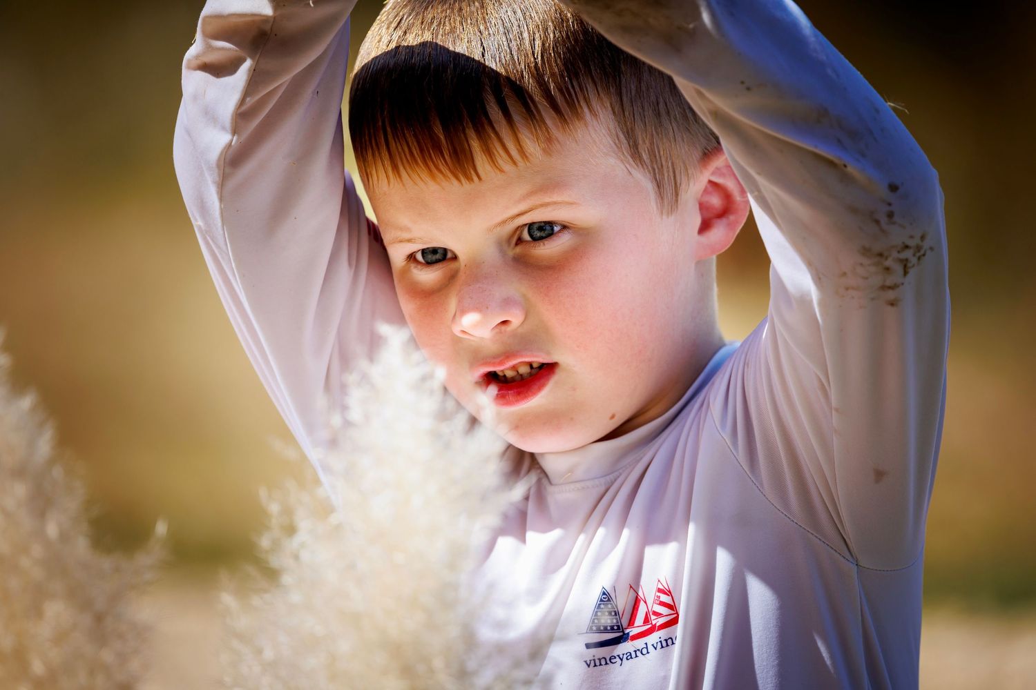 Close up view of child playing with floating seeds in sunlight while wearing white.