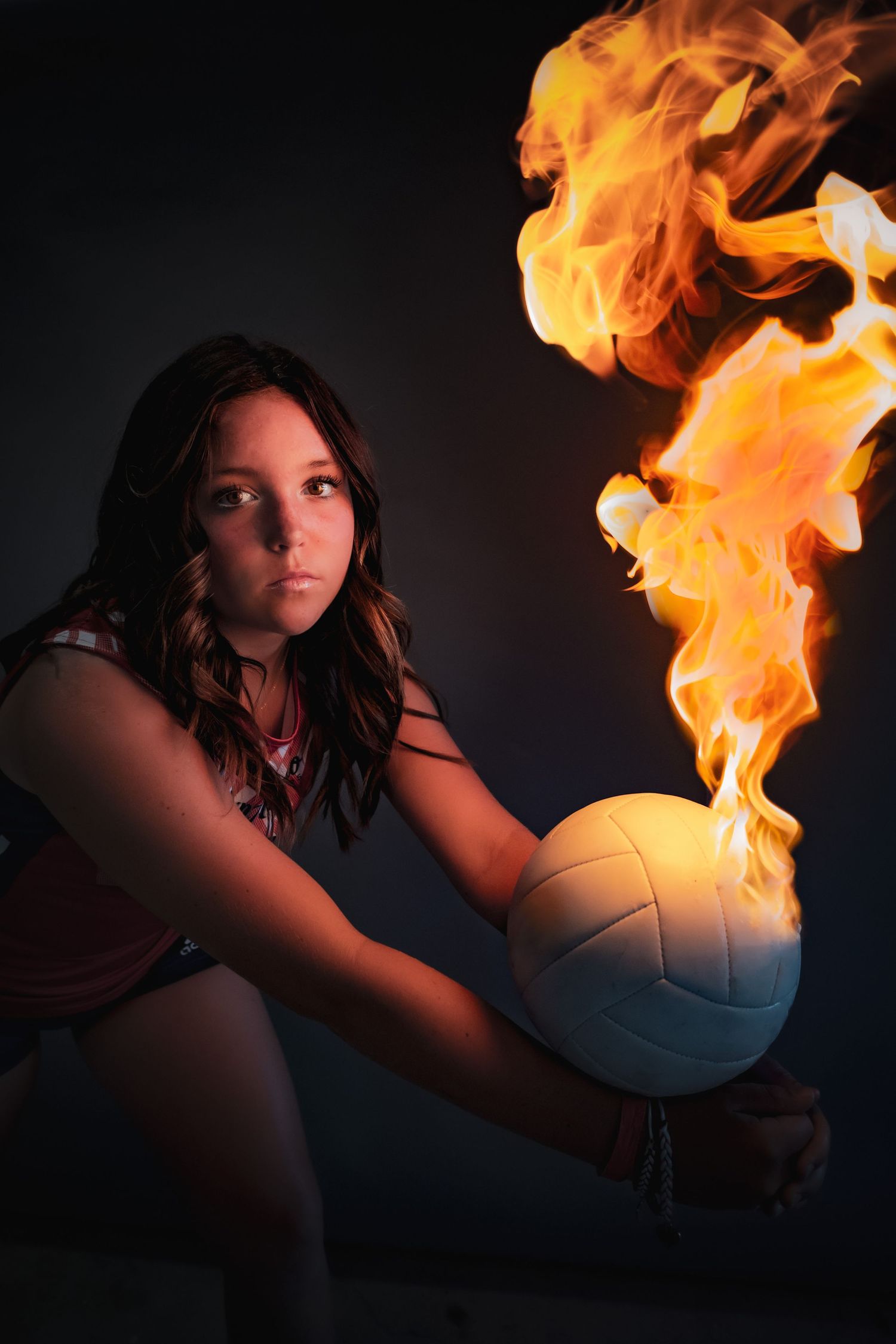 A dramatic sports photo featuring a volleyball engulfed in flames against a dark background.