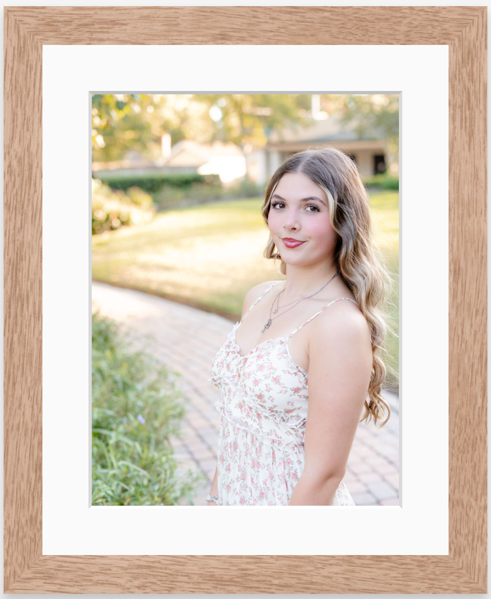 Young woman in floral dress poses on brick path in framed portrait photo.