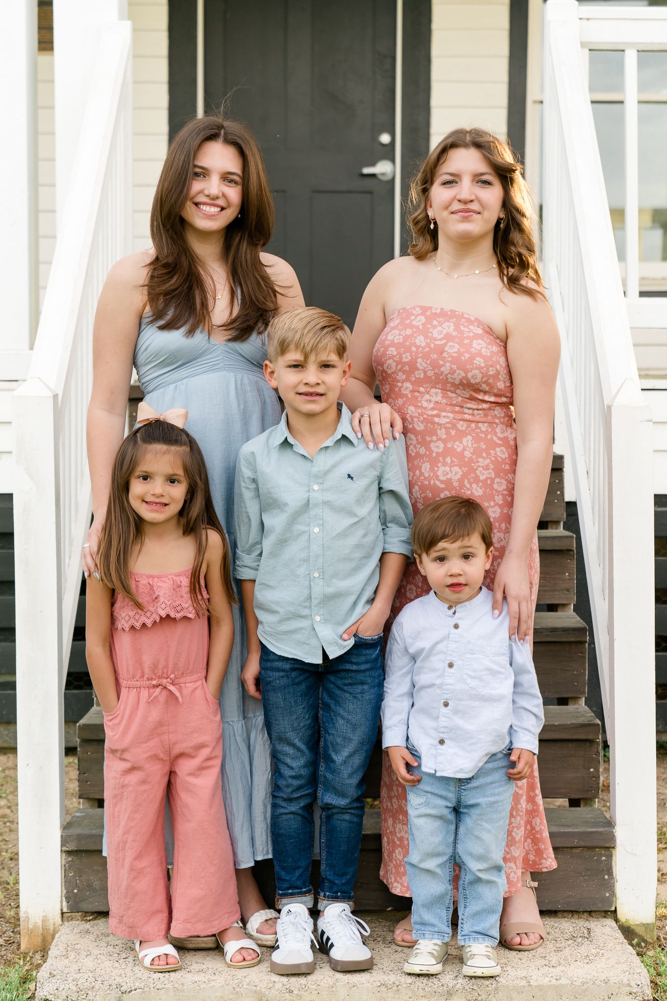 Five siblings posing on front porch steps, two teenage girls with three younger children in coordinated outfits.
