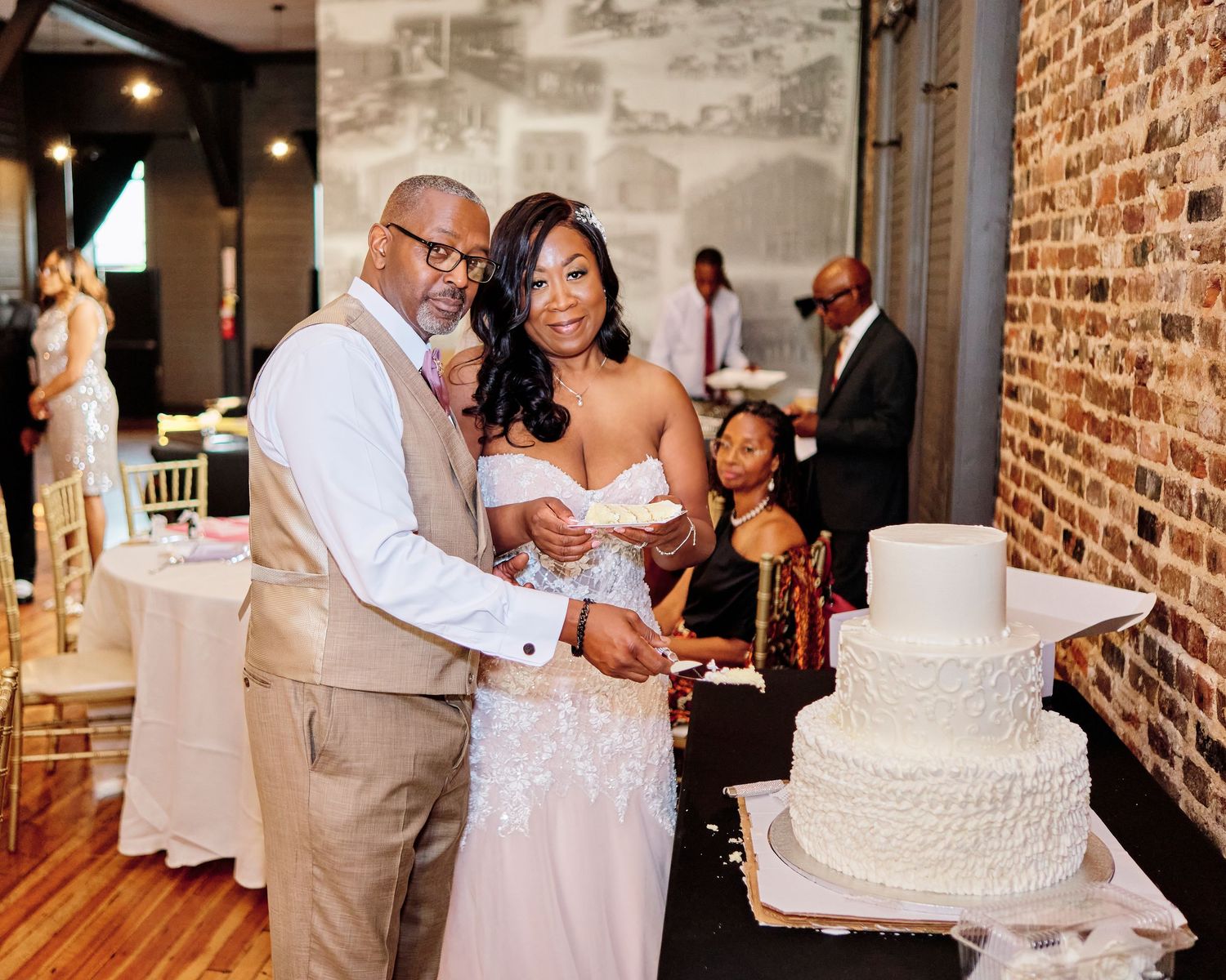 Wedding reception scenes showing the couple cutting their cake and dancing in a rustic brick venue.