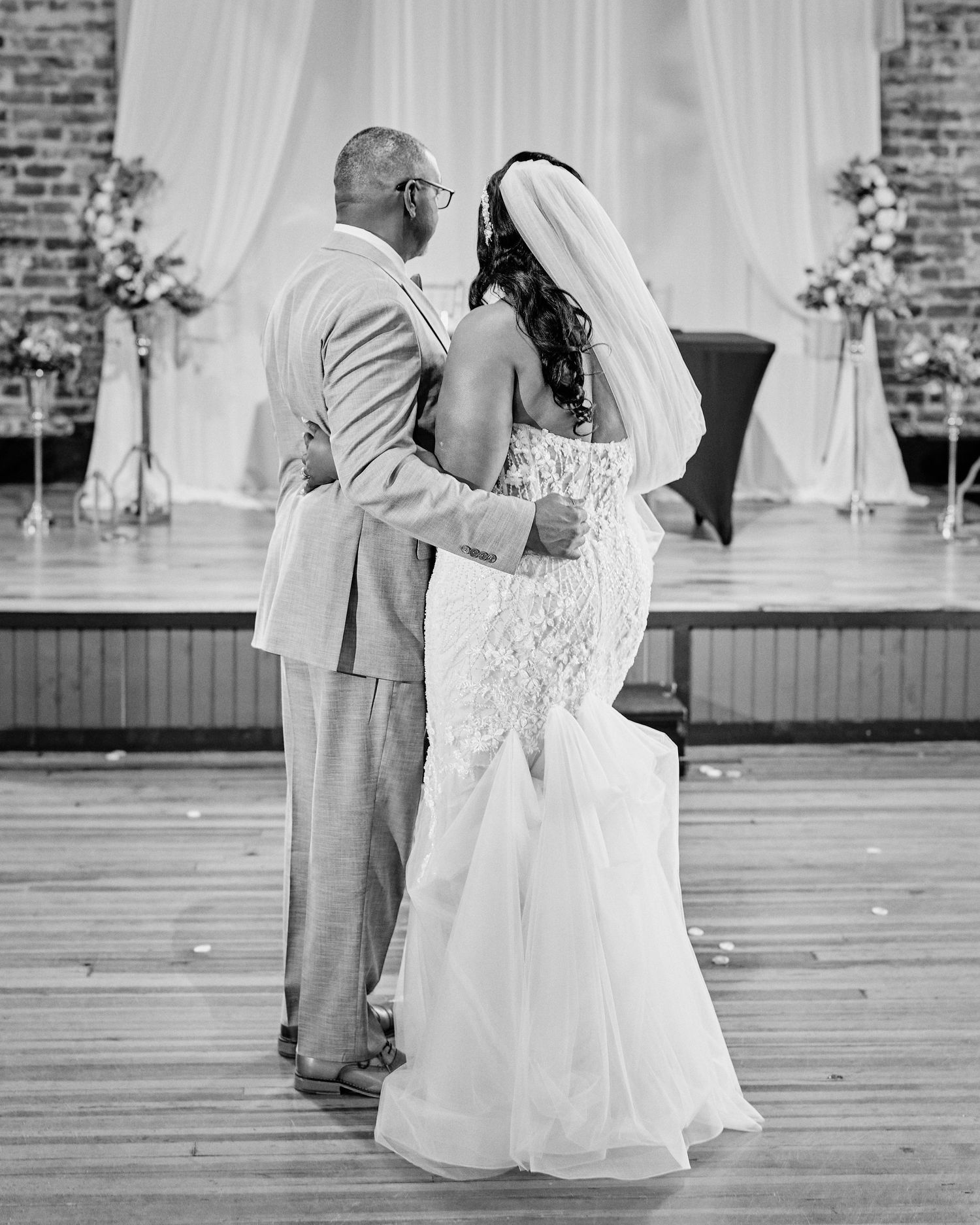 Black and white photos of a couple sharing their first dance at a wedding reception with brick wall backdrop.