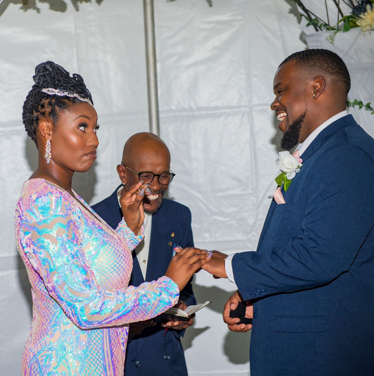 A couple exchanges rings during an emotional wedding ceremony with an officiant.