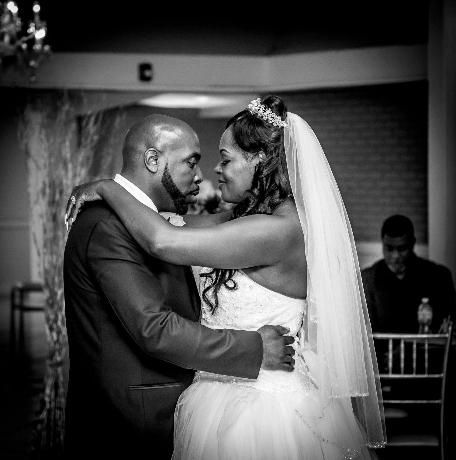 A couple shares a romantic dance moment at their wedding reception in black and white.