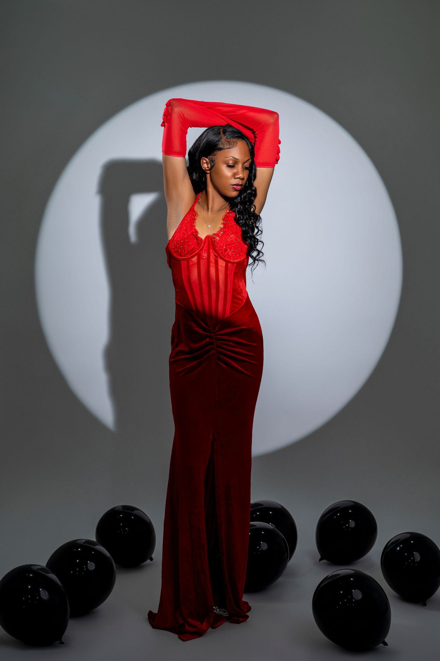 Fashion portrait series in red gown against grey backdrop with dramatic lighting.