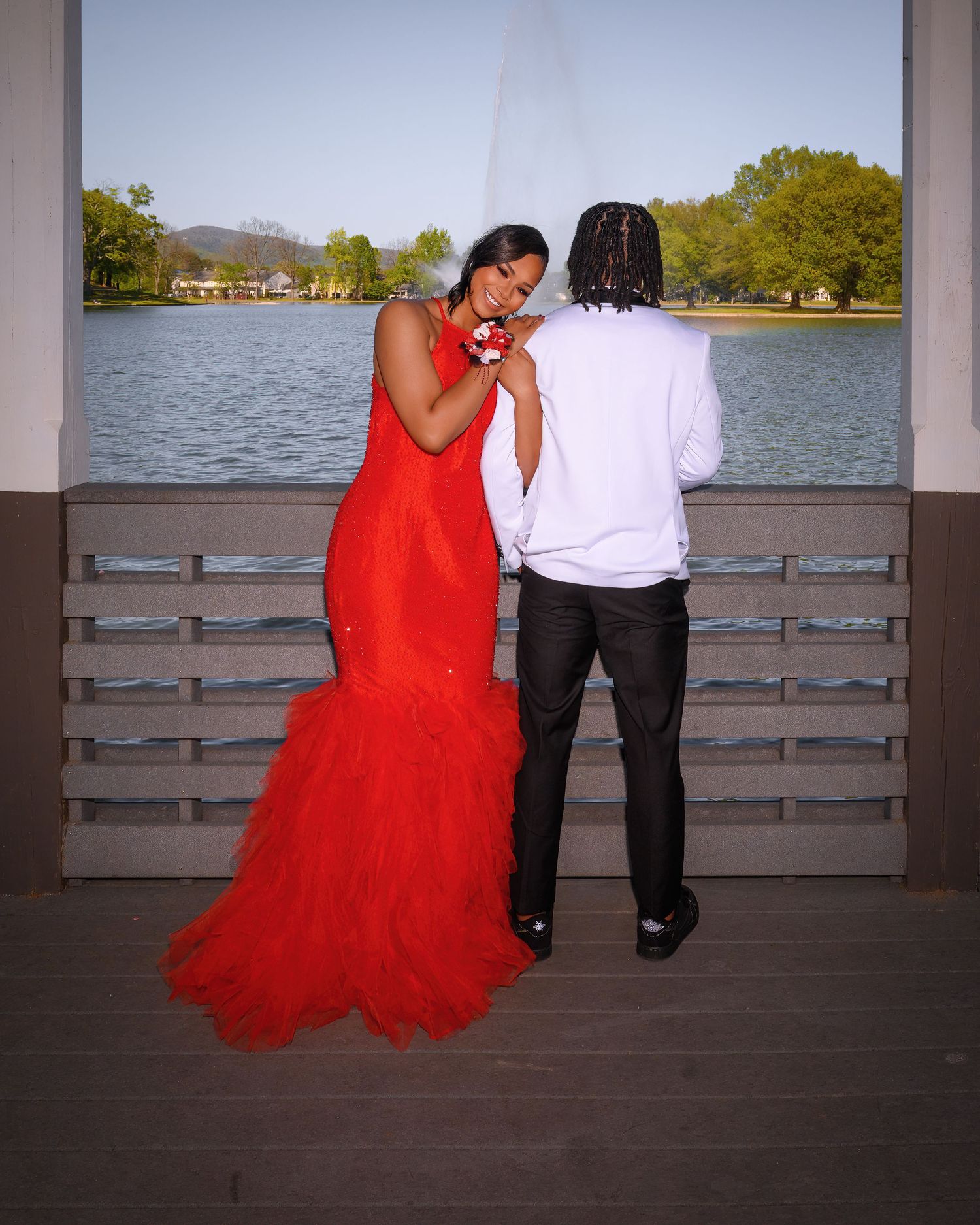 Couple sharing romantic moment on lakeside deck with mountains in background.