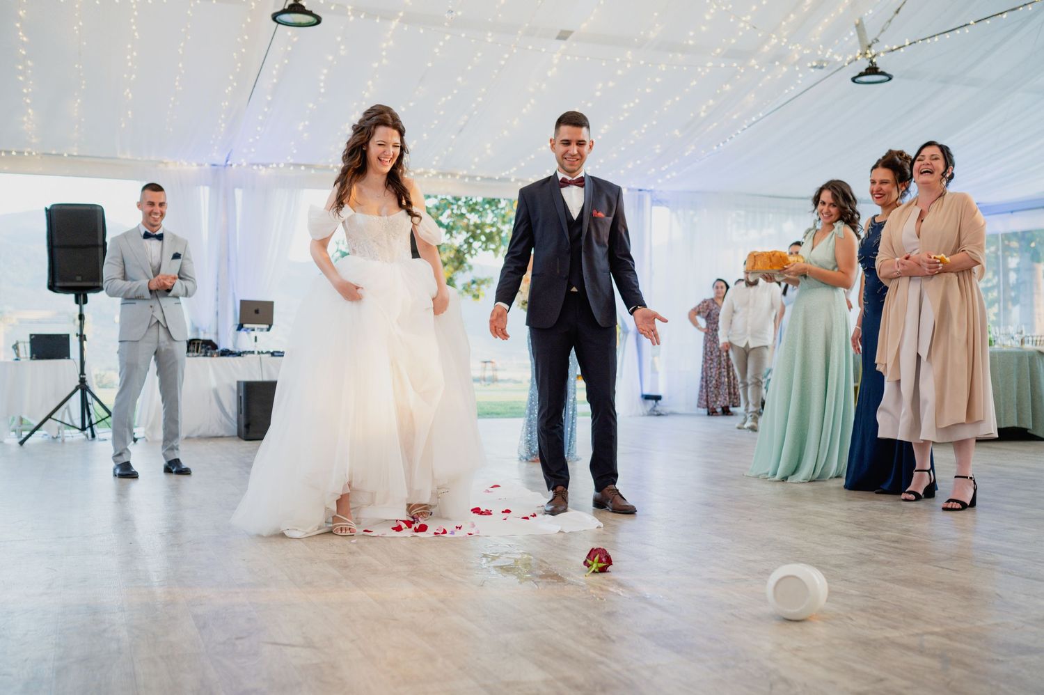 Wedding guests dancing on a bright white dance floor under a reception tent.