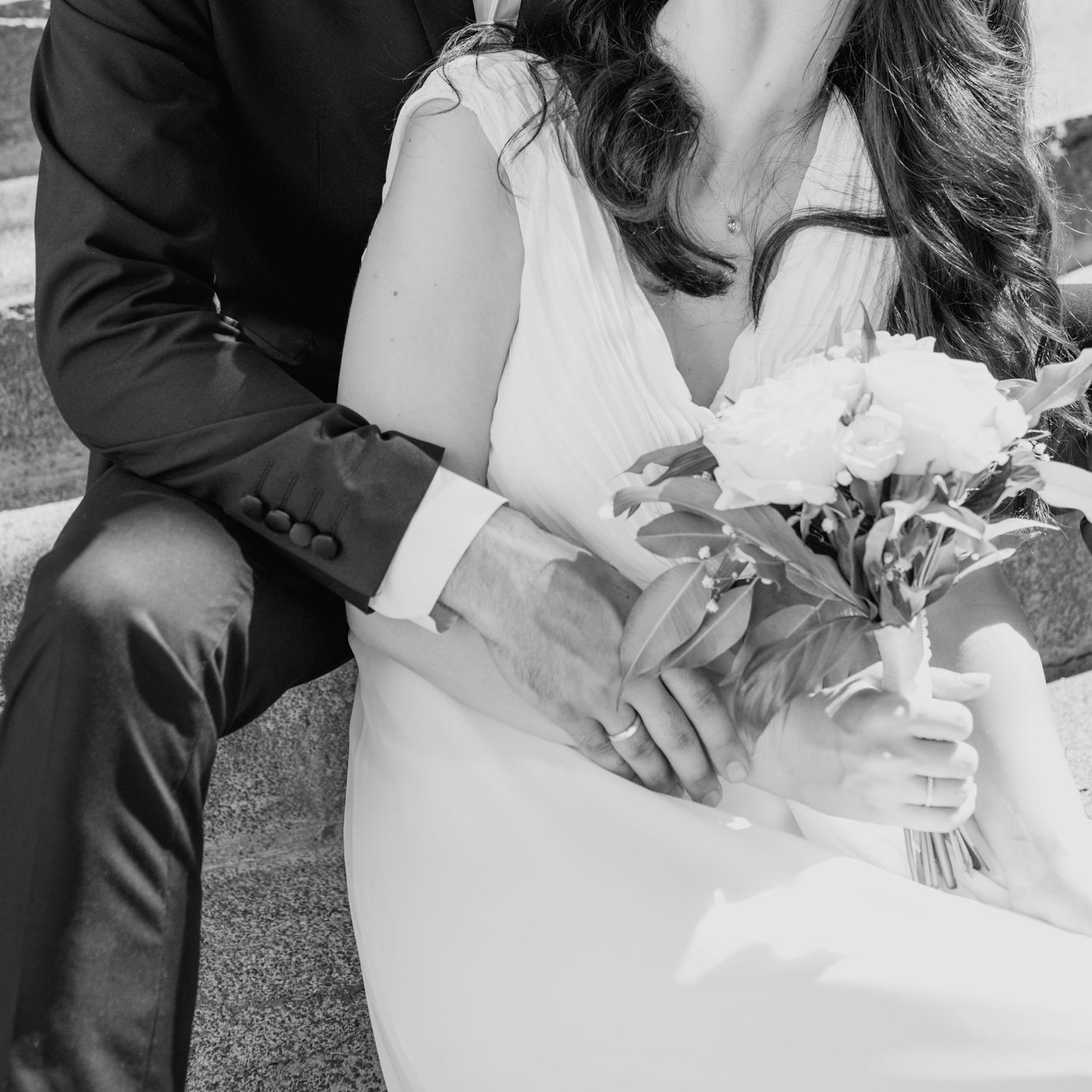 Close-up wedding photography of a white dress and floral bouquet details.