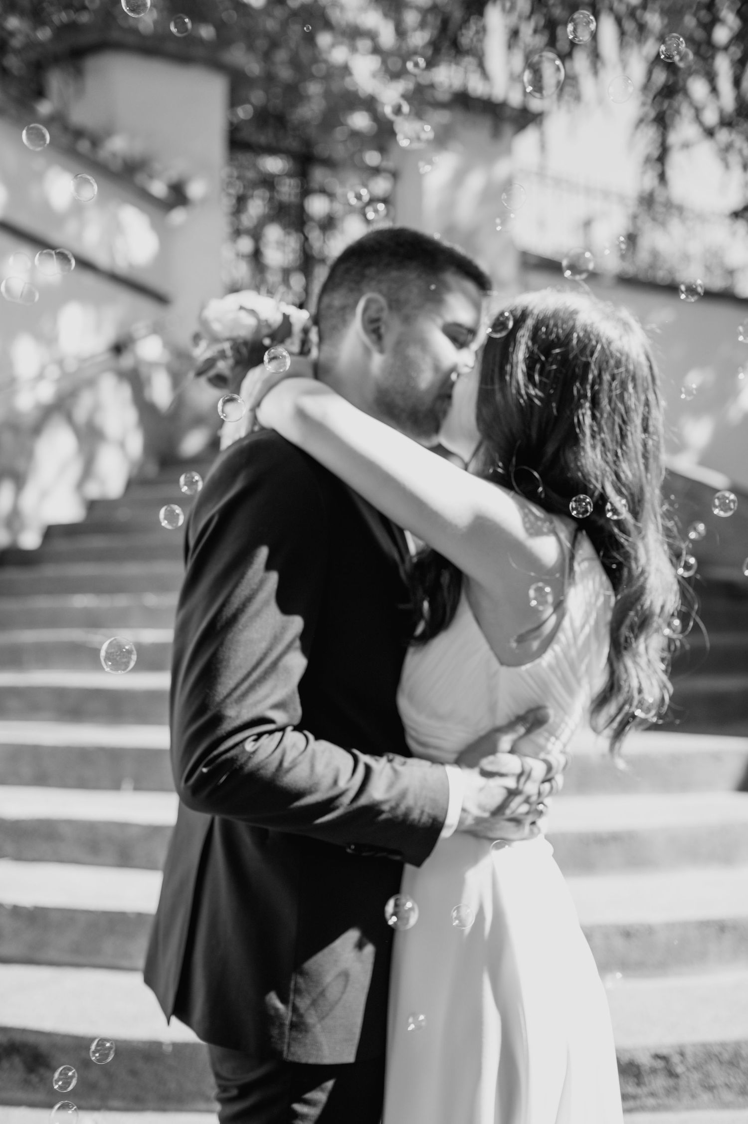 A romantic moment captured with floating bubbles during an outdoor wedding celebration.