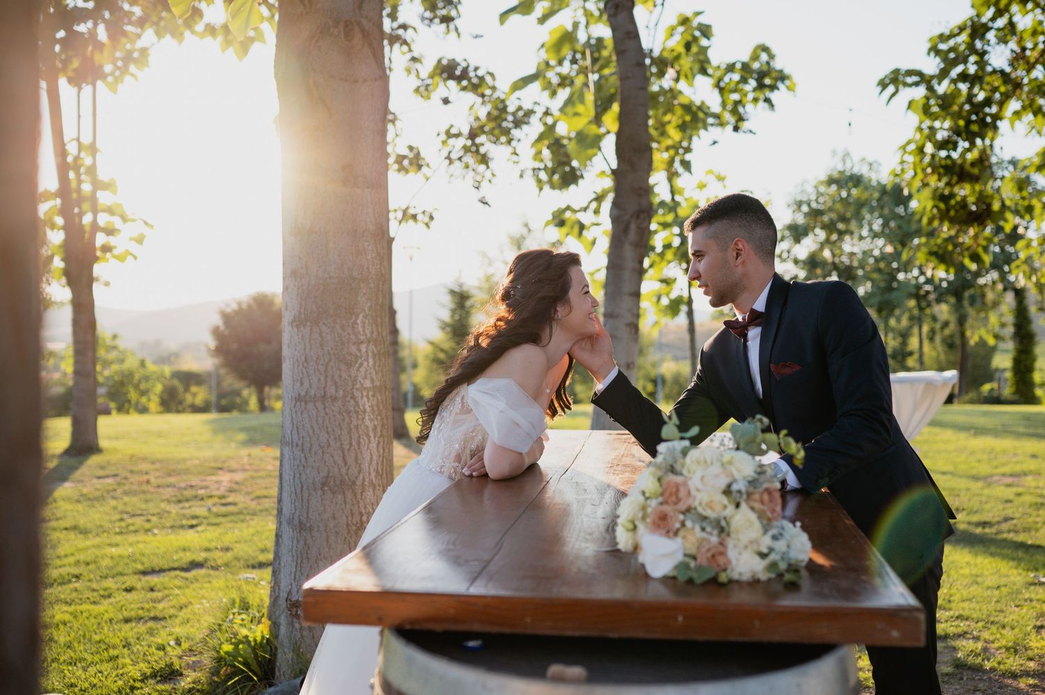 Couple dances at sunset in an outdoor garden setting with palm trees.