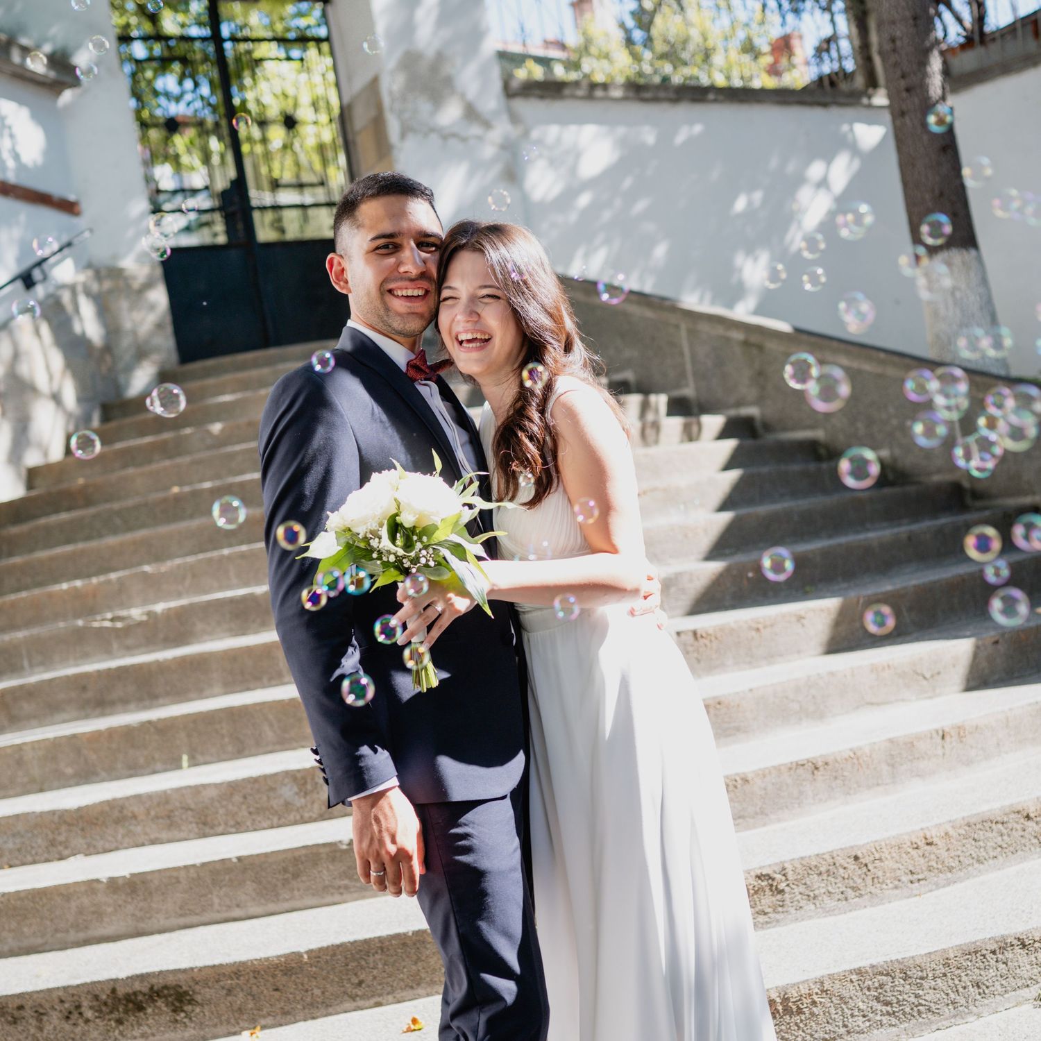Bubbles float around a couple during their outdoor wedding photoshoot.