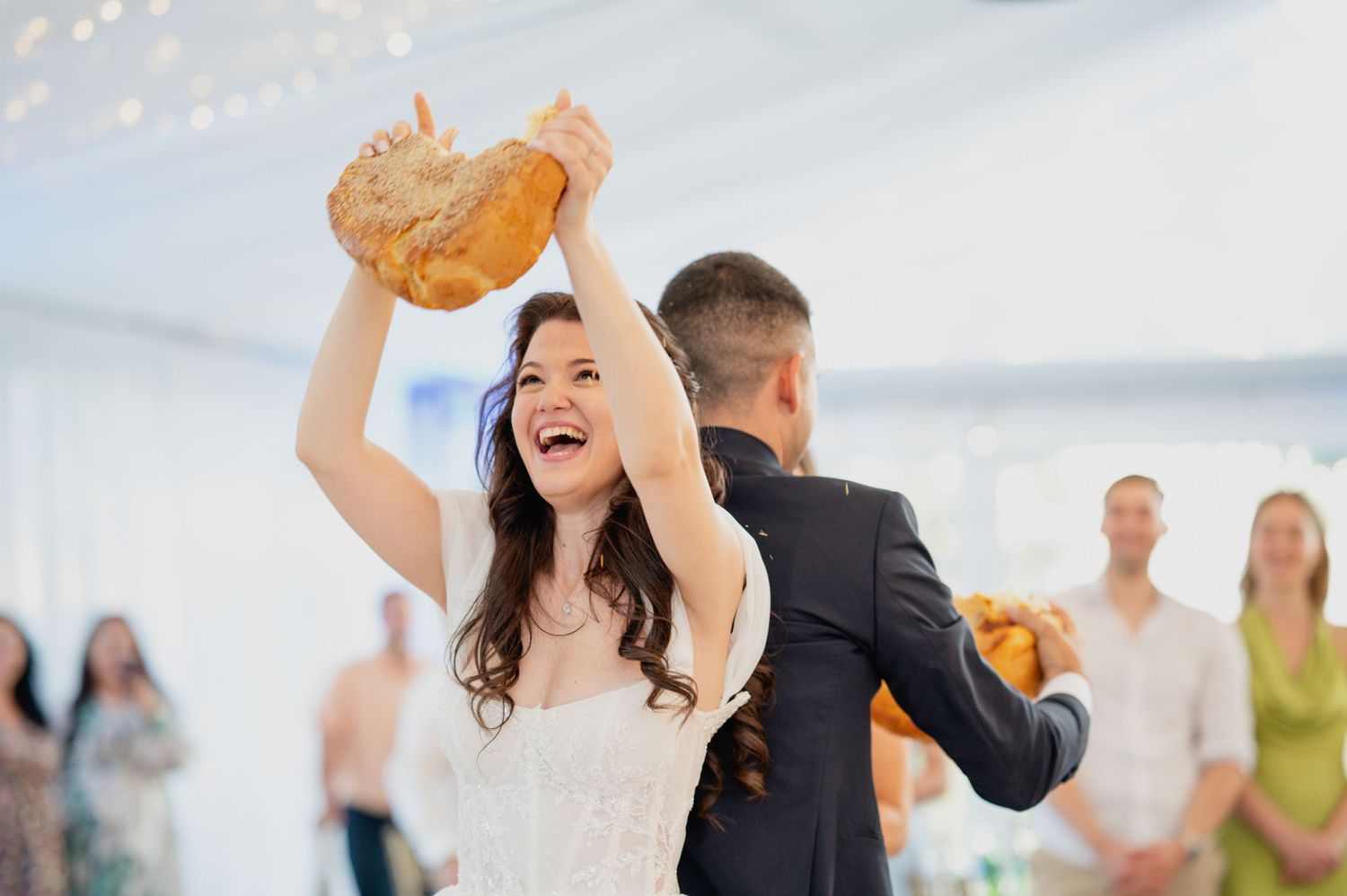 Wedding reception celebration under a white tent with dancing couples.