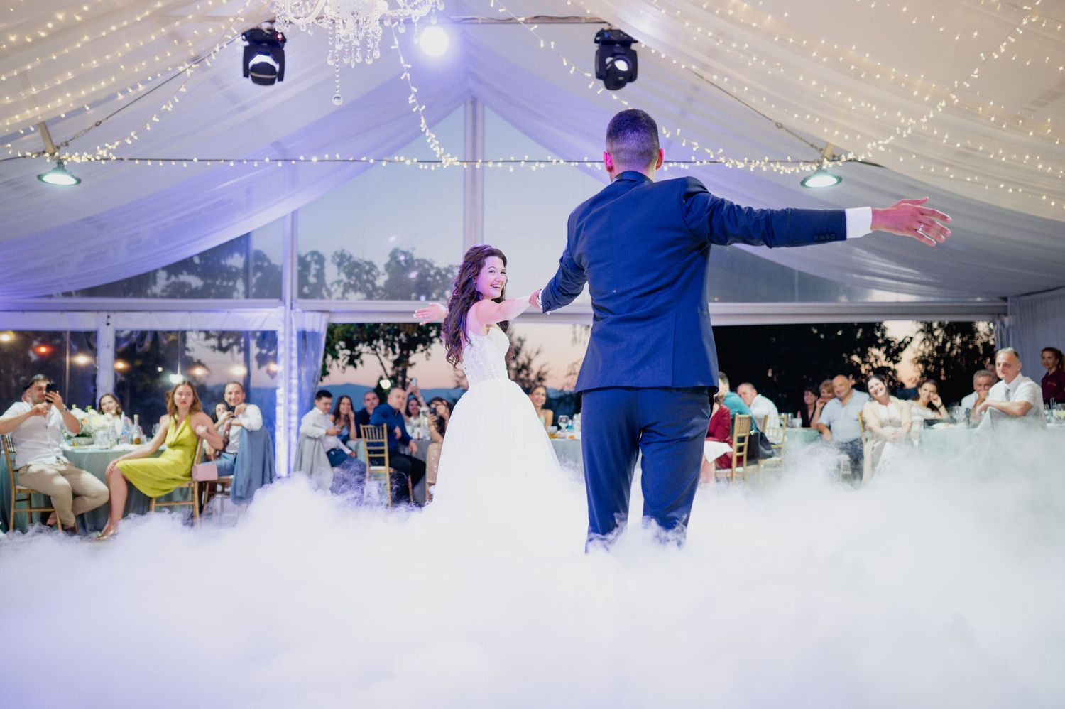 Wedding reception dance floor under string lights in an elegant white tent.