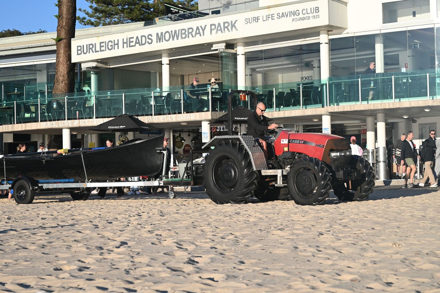 Red tractor hauls a surf boat at Burleigh Heads Mowbray Park Surf Life Saving Club beach.