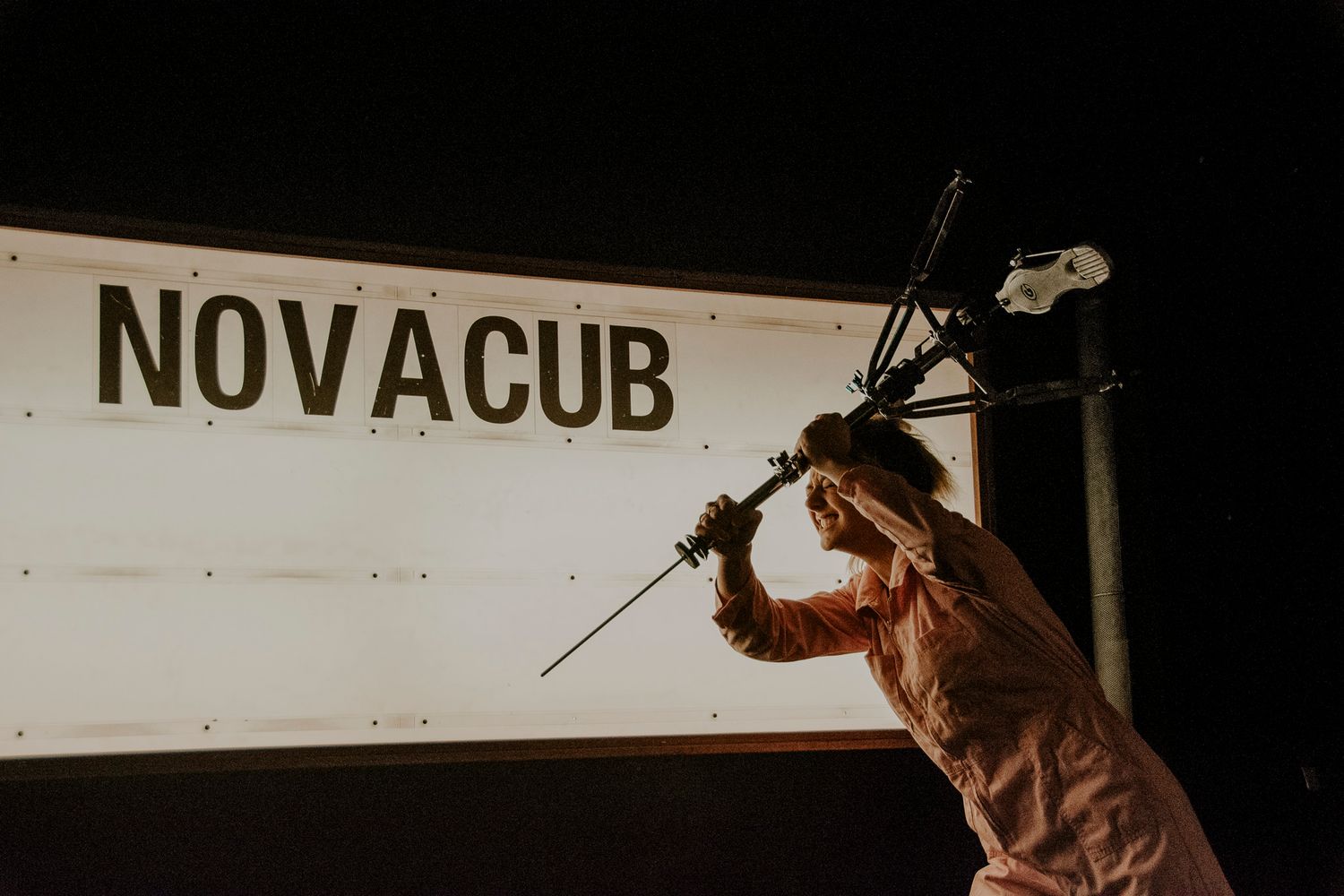 Silhouette of performer against NOVACUB sign in dramatic lighting.