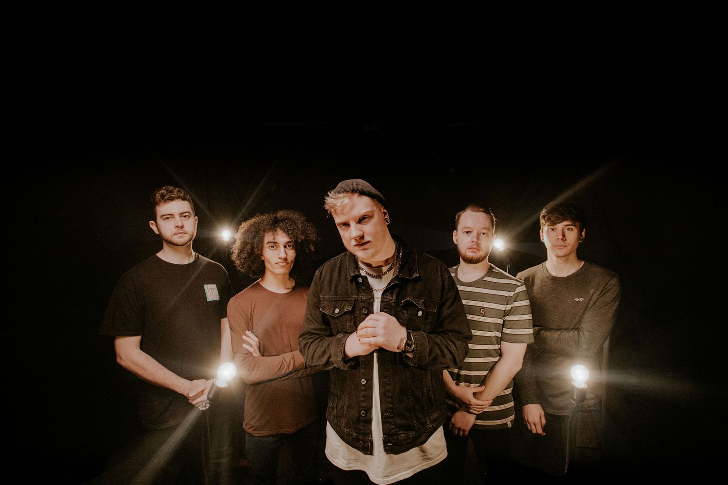Dissonants poses with flashlights for a moody promotional photo in darkness.