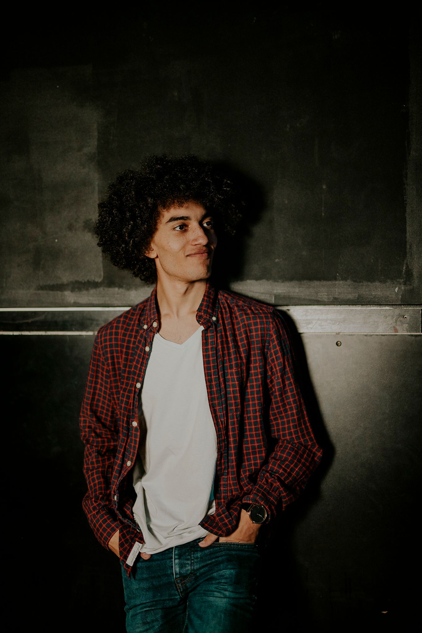 Disonnants ex-drummer wearing a red plaid shirt and white t-shirt against a dark background.
