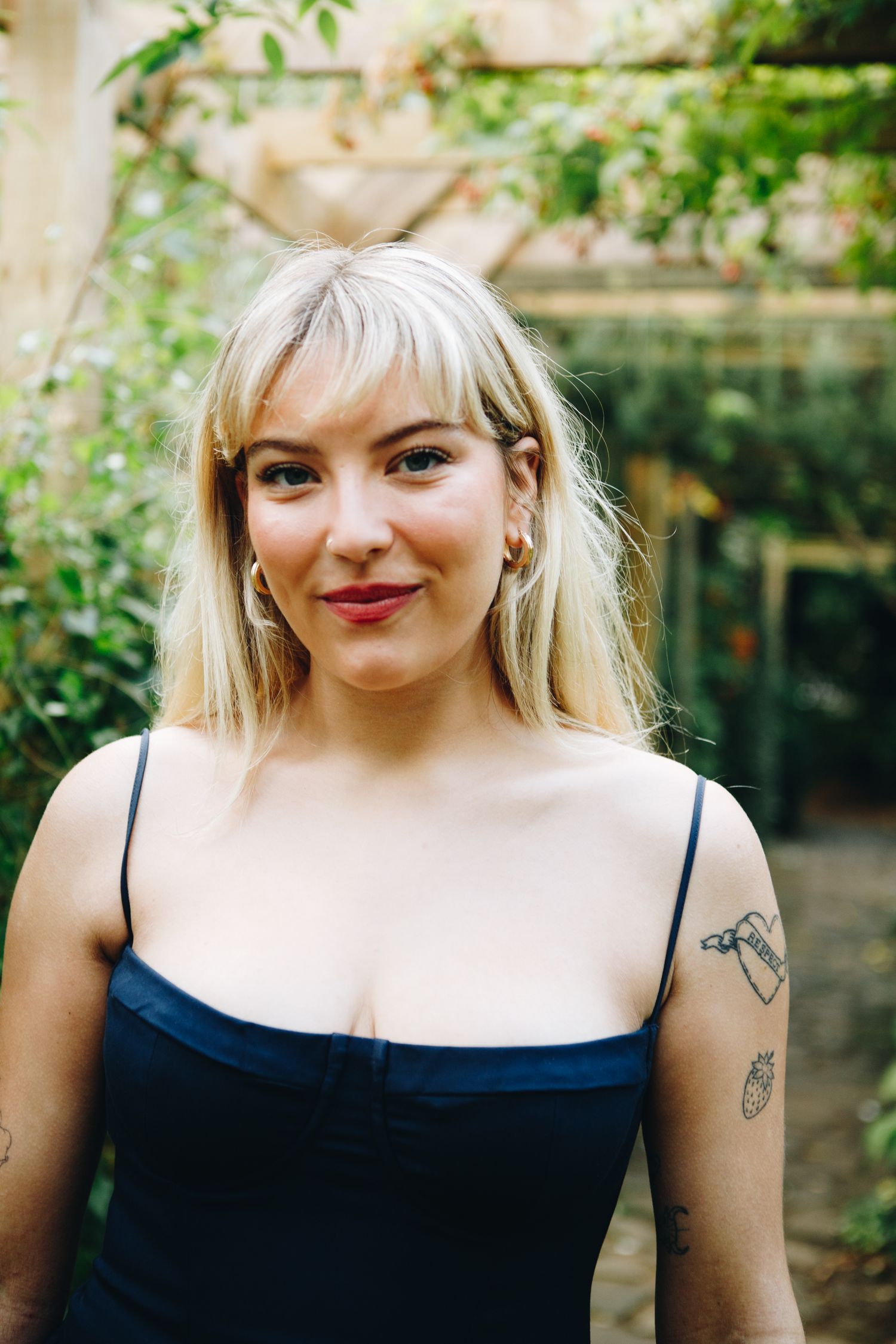 Cate Canning in black dress poses in garden setting with natural lighting.