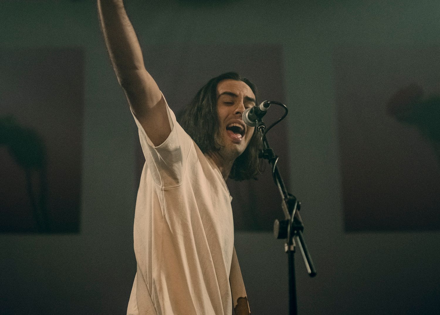 With Confidence performing with raised arm against simple studio backdrop.