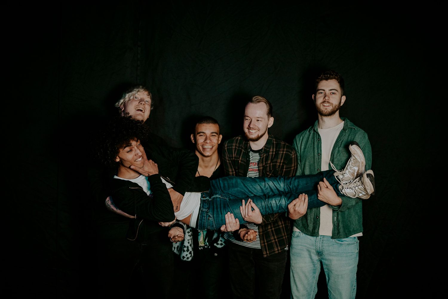 Dissonants holding each other playfully against a dark background.