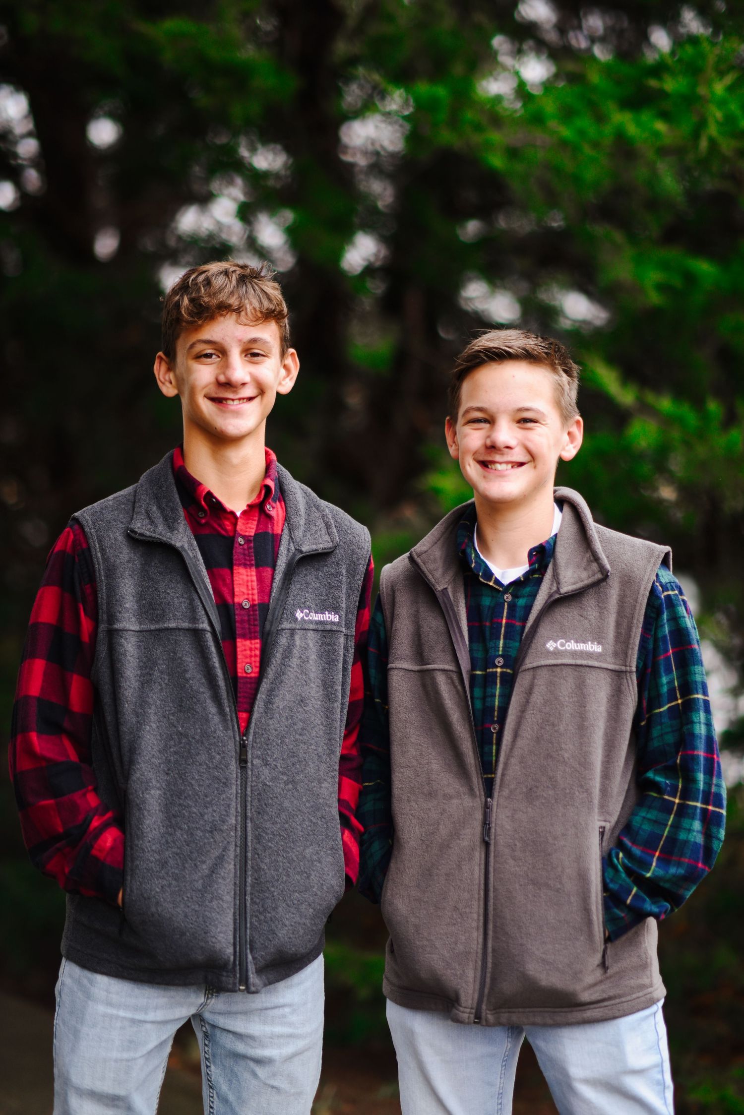 Two teenage boys wearing matching Columbia fleece vests smiling outdoors.