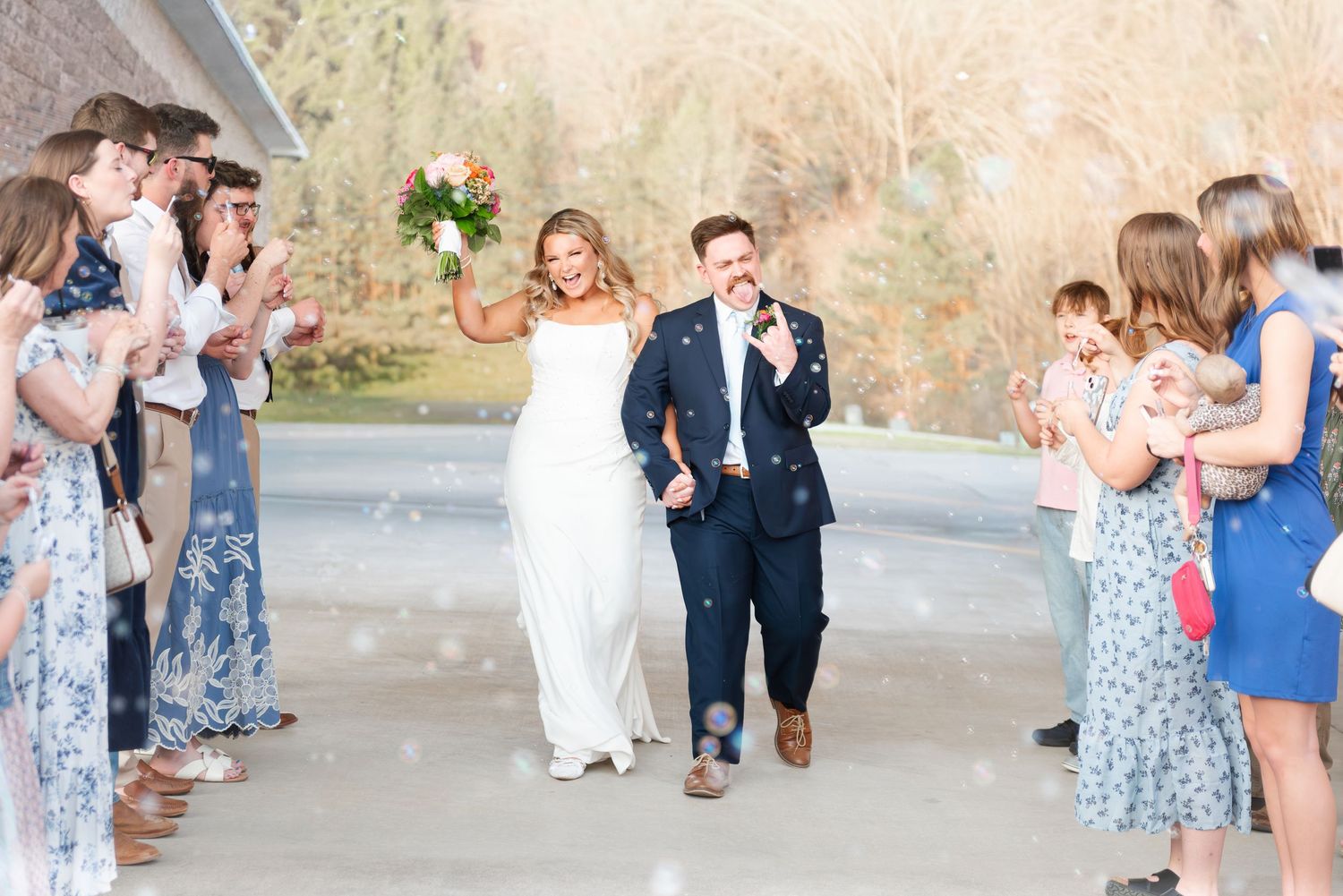 Bride and groom celebrate joyful confetti exit as wedding guests cheer along the pathway.