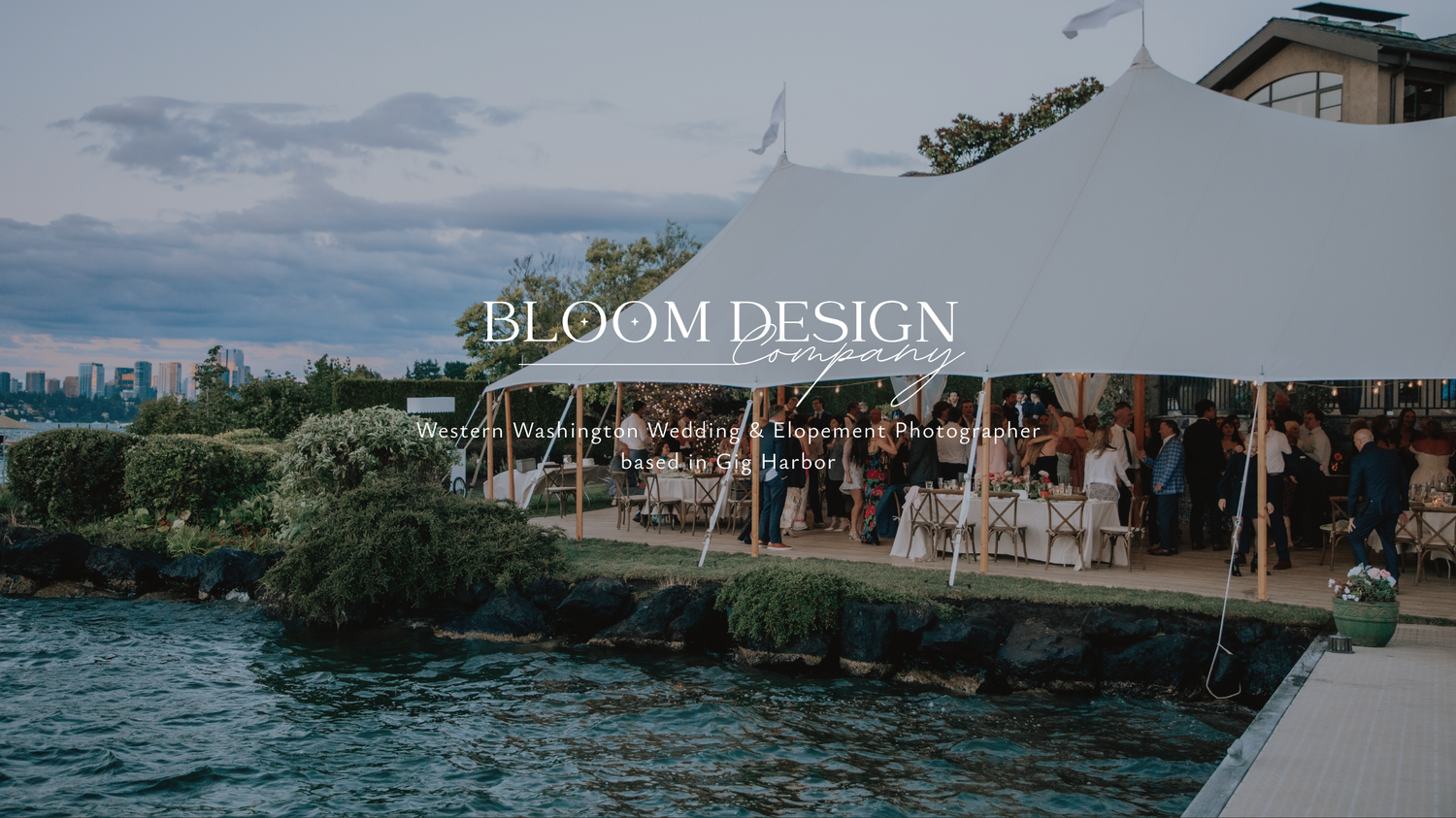 Bloom Design Co outdoor waterfront wedding reception under a white tent with city skyline views.