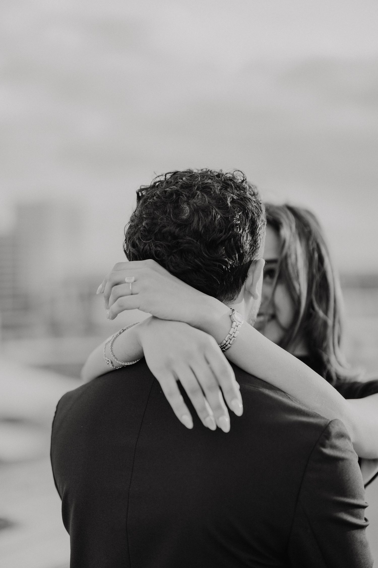 Black and white photo of a tender embrace, showing someone's arms wrapped around another person's shoulders.