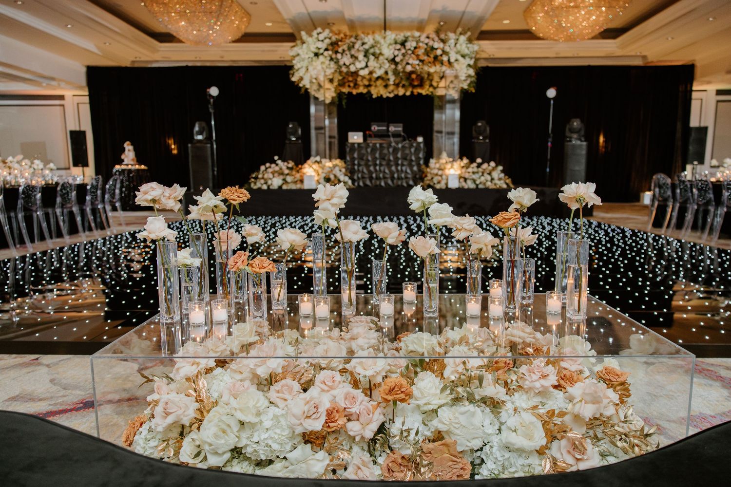 Luxurious wedding reception table with crystal glassware and white floral centerpieces under ornate ceiling decor.
