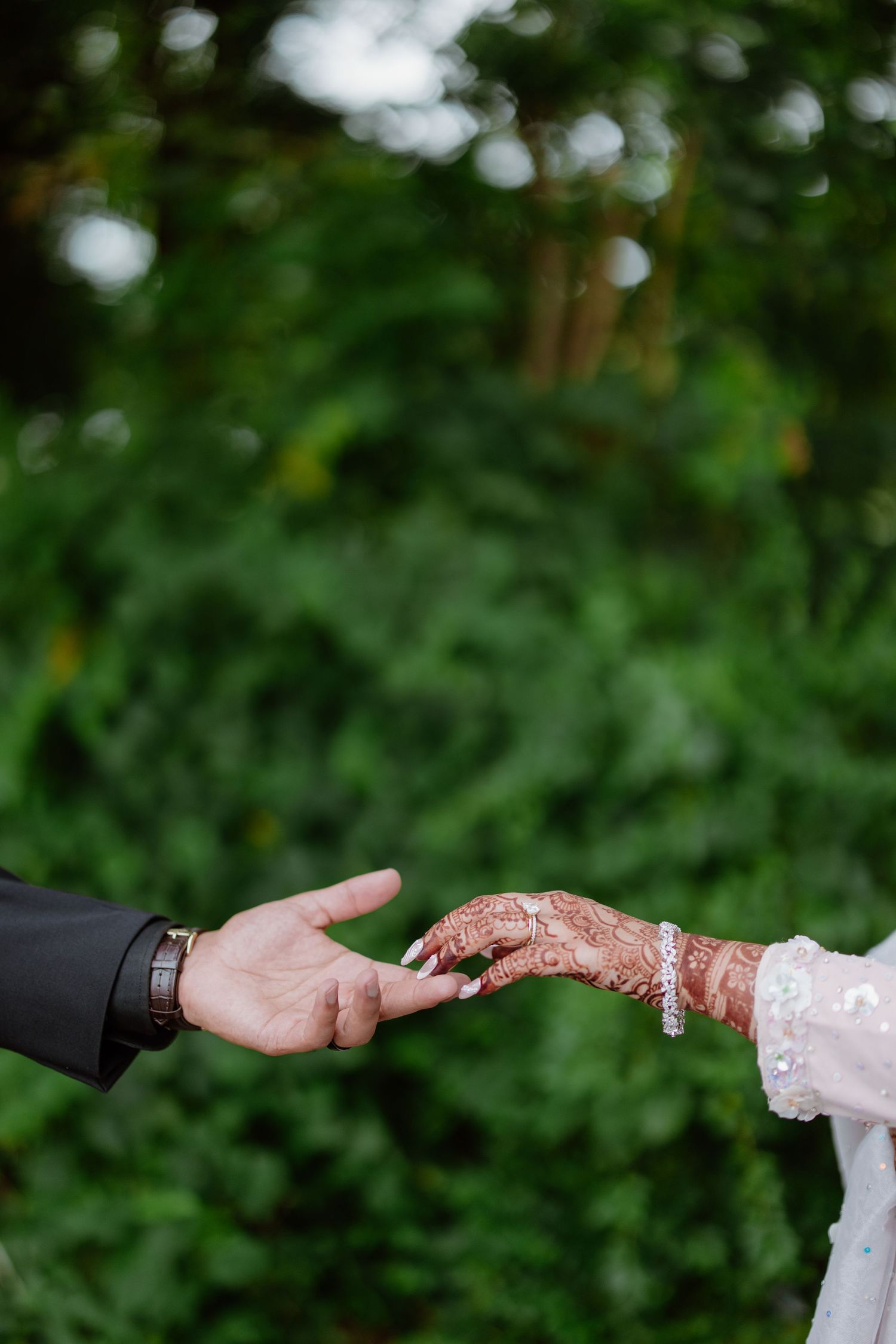Close-up of hands exchanging rings during an outdoor wedding ceremony.