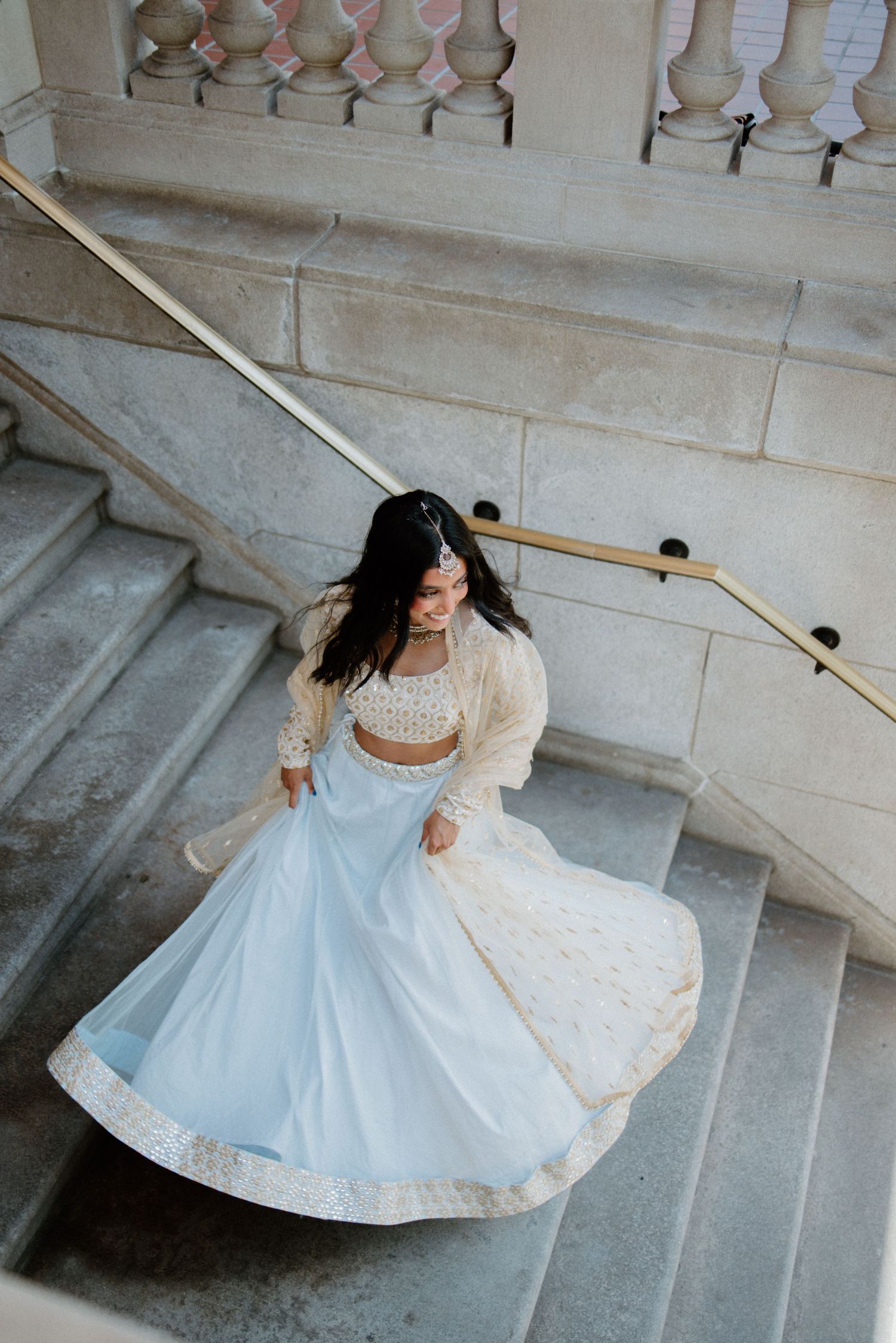 A person in a light blue and white dress spins gracefully on stone steps, creating a flowing circular motion effect.