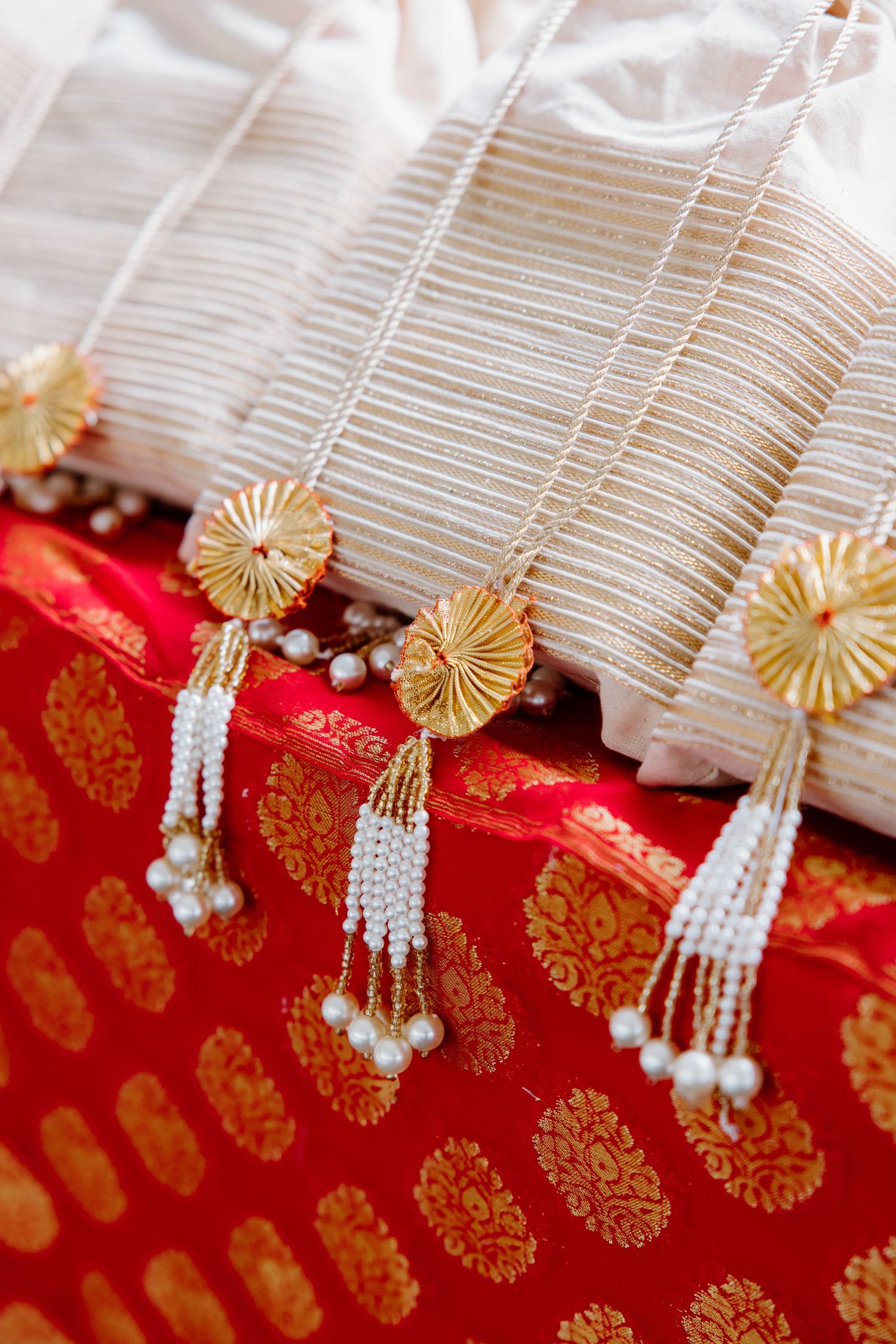 Close-up detail of traditional Japanese shinto wedding decor with white and gold paper ornaments against red fabric.