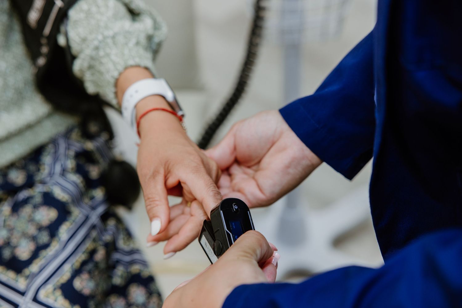 Close-up shot of hands putting on a navy blue smart watch with a leather band.